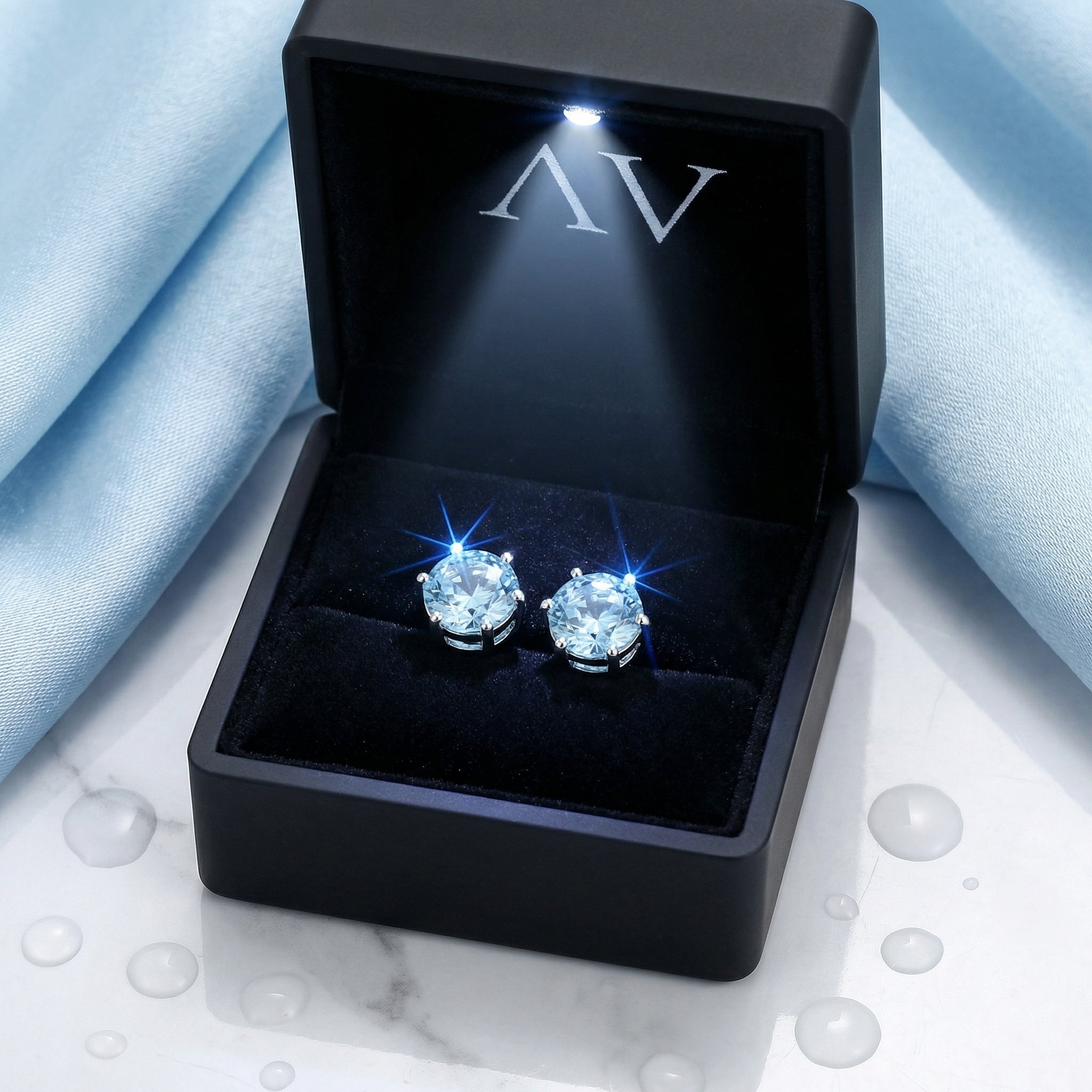 Pair of round cut simulated aquamarine studs displayed in a premium black LED-lit jewelry presentation box.