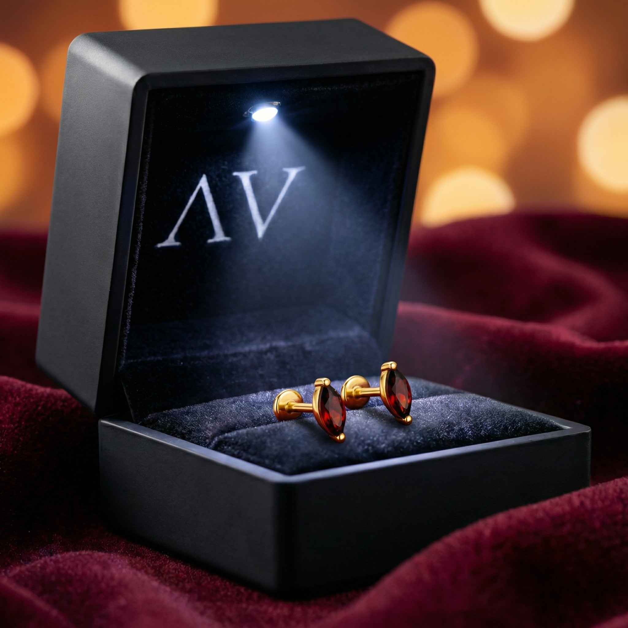 Marquise cut simulated garnet earrings in 18K gold vermeil inside a lighted black jewelry box.