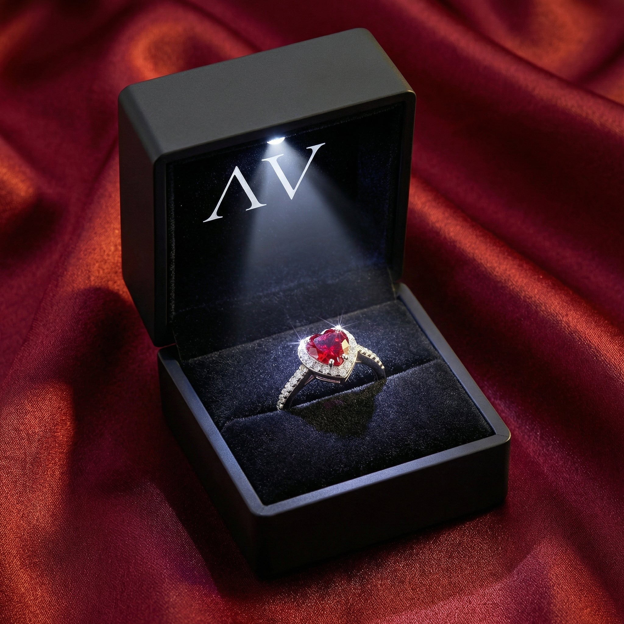 Heart-shaped simulated ruby ring presented in a black LED-lit jewelry box on red silk.