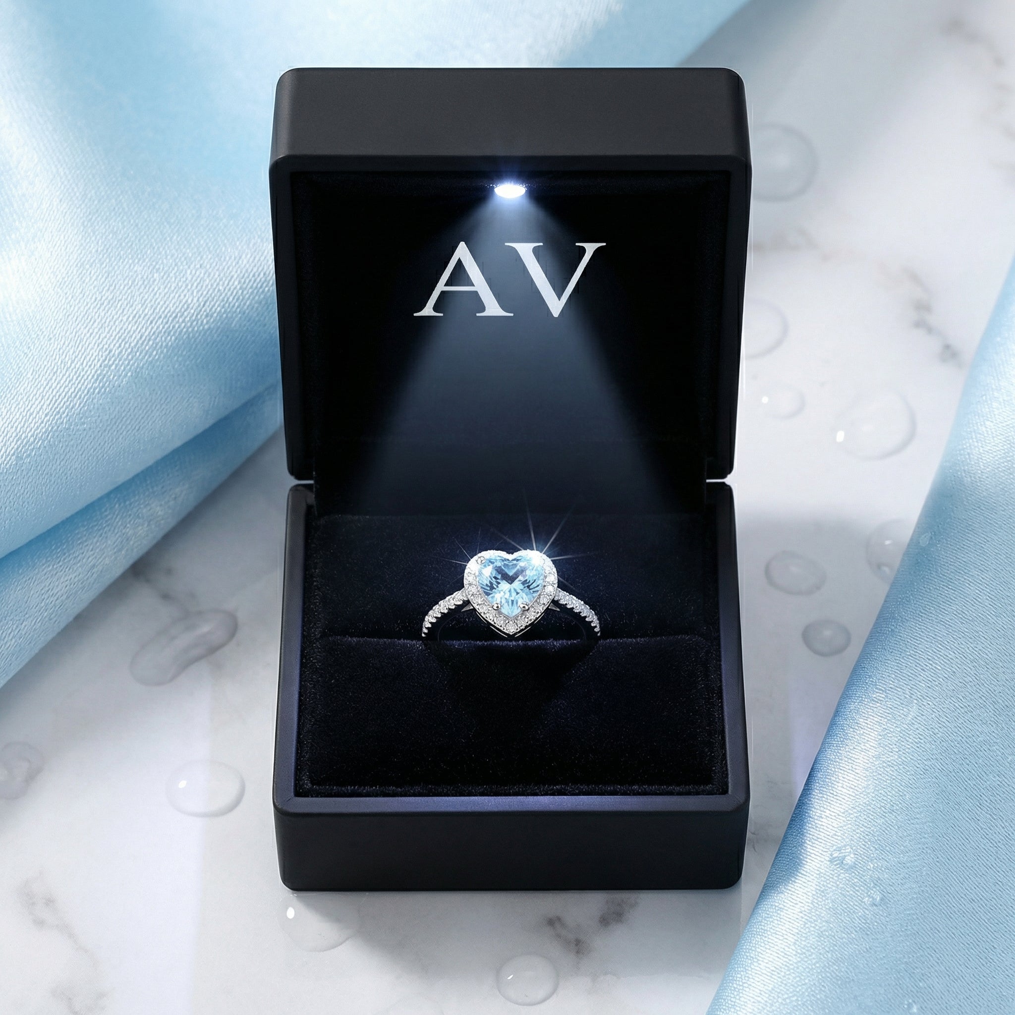 Heart-cut simulated aquamarine sterling silver ring inside a black LED-lit jewelry gift box.
