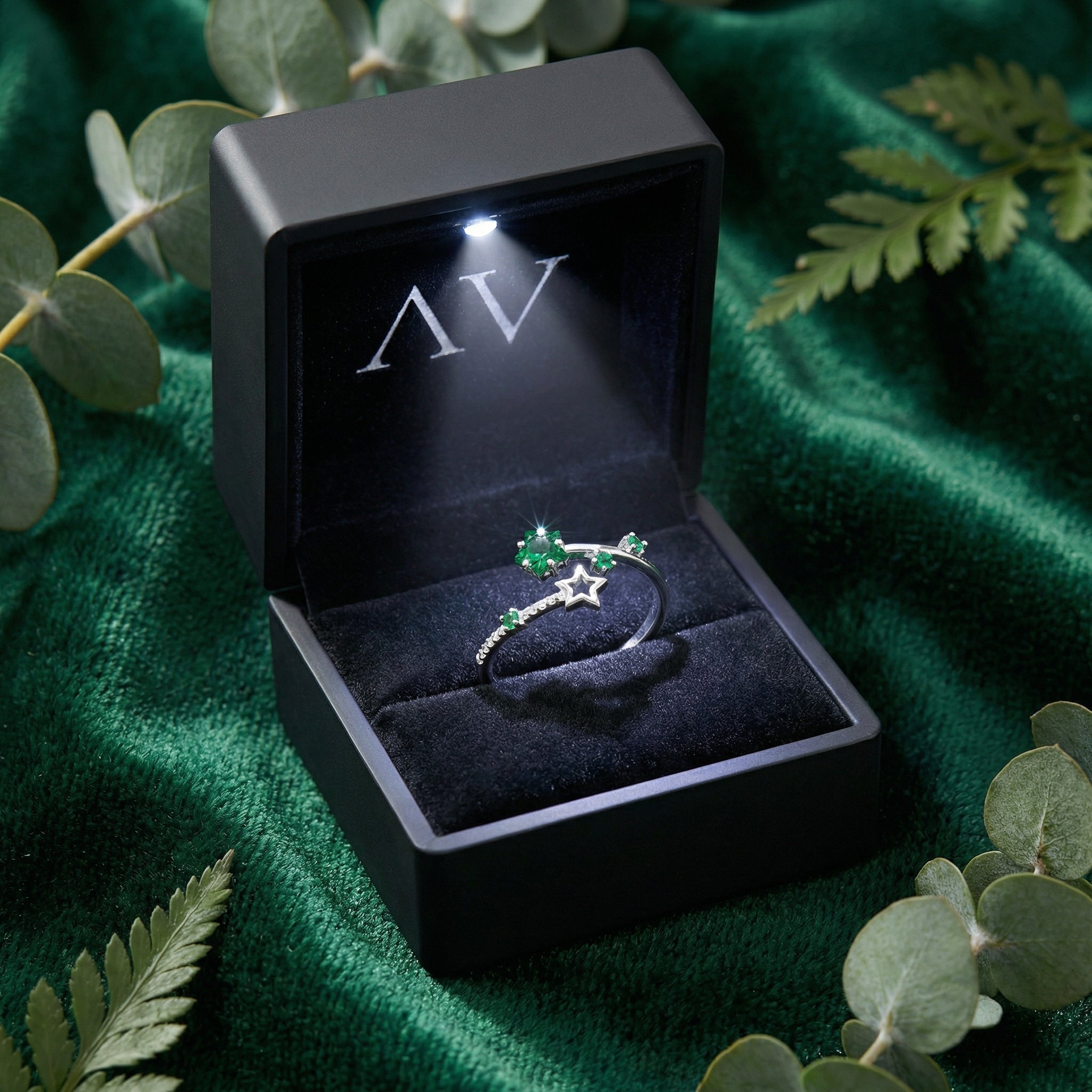 Adjustable silver star ring with green simulated emeralds presented in a premium black LED-lit gift box.
