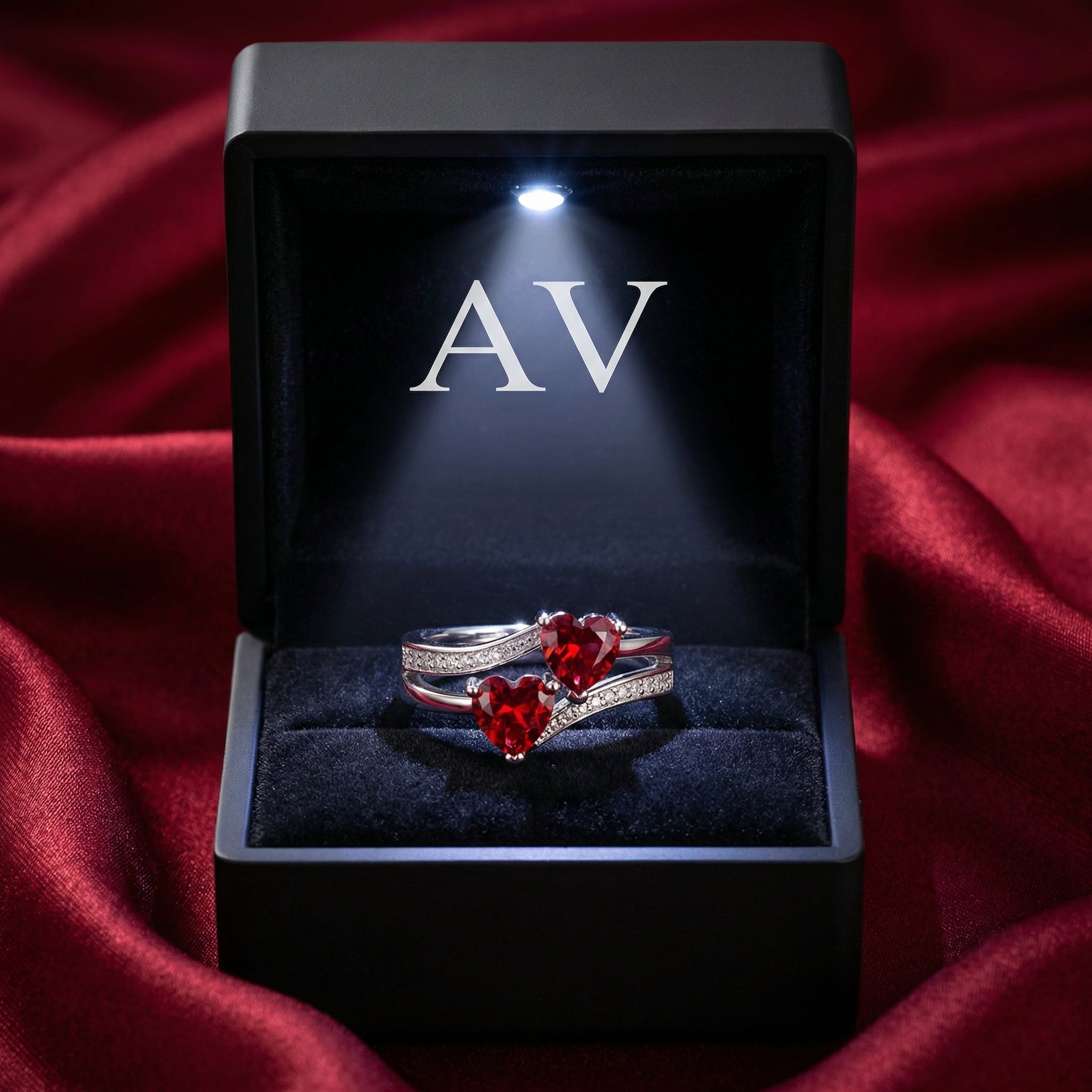 Elianara heart ring with simulated rubies inside a black LED-lighted jewelry box on red satin.