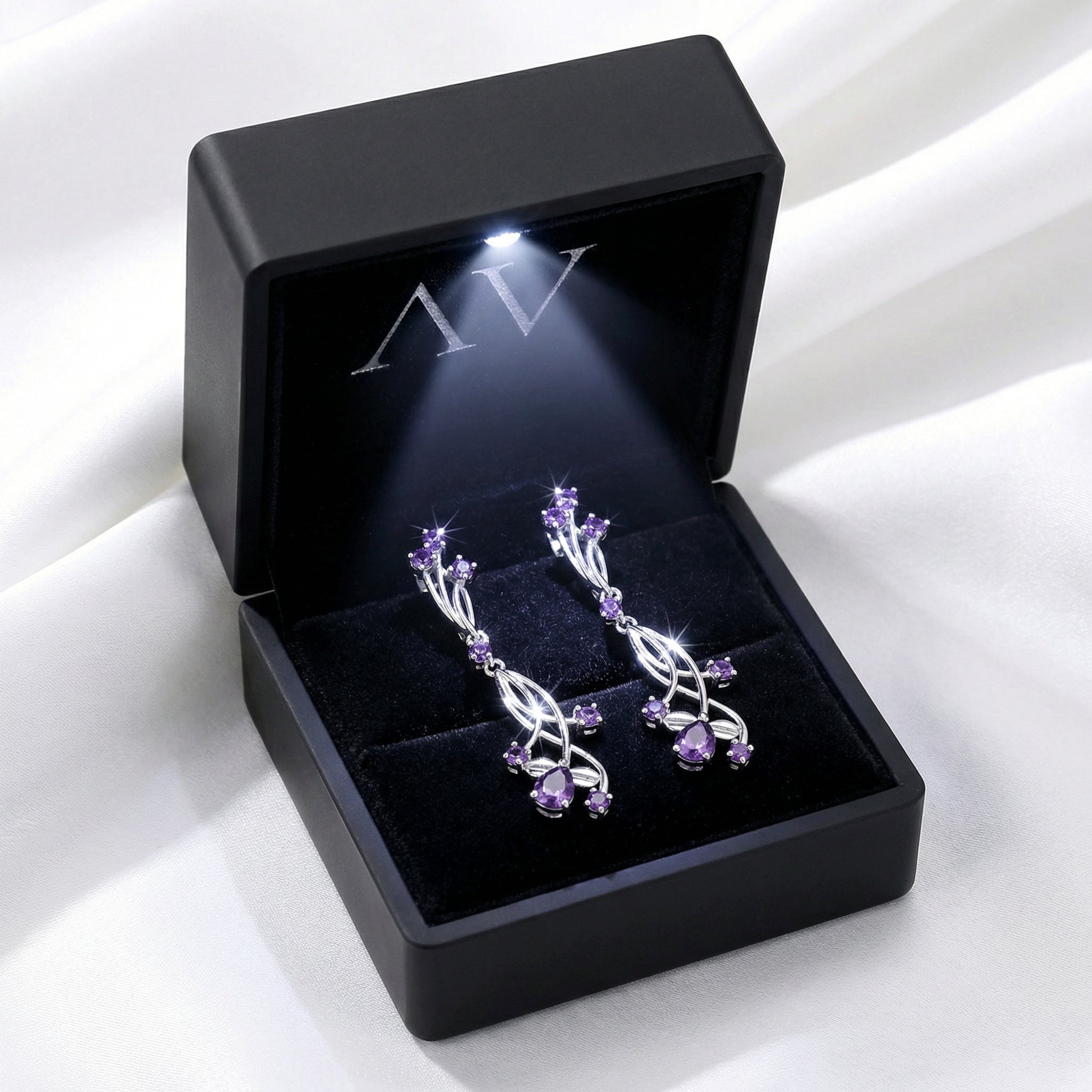 The Lyriel Drops sterling silver earrings displayed in a black jewelry box with an integrated LED light.