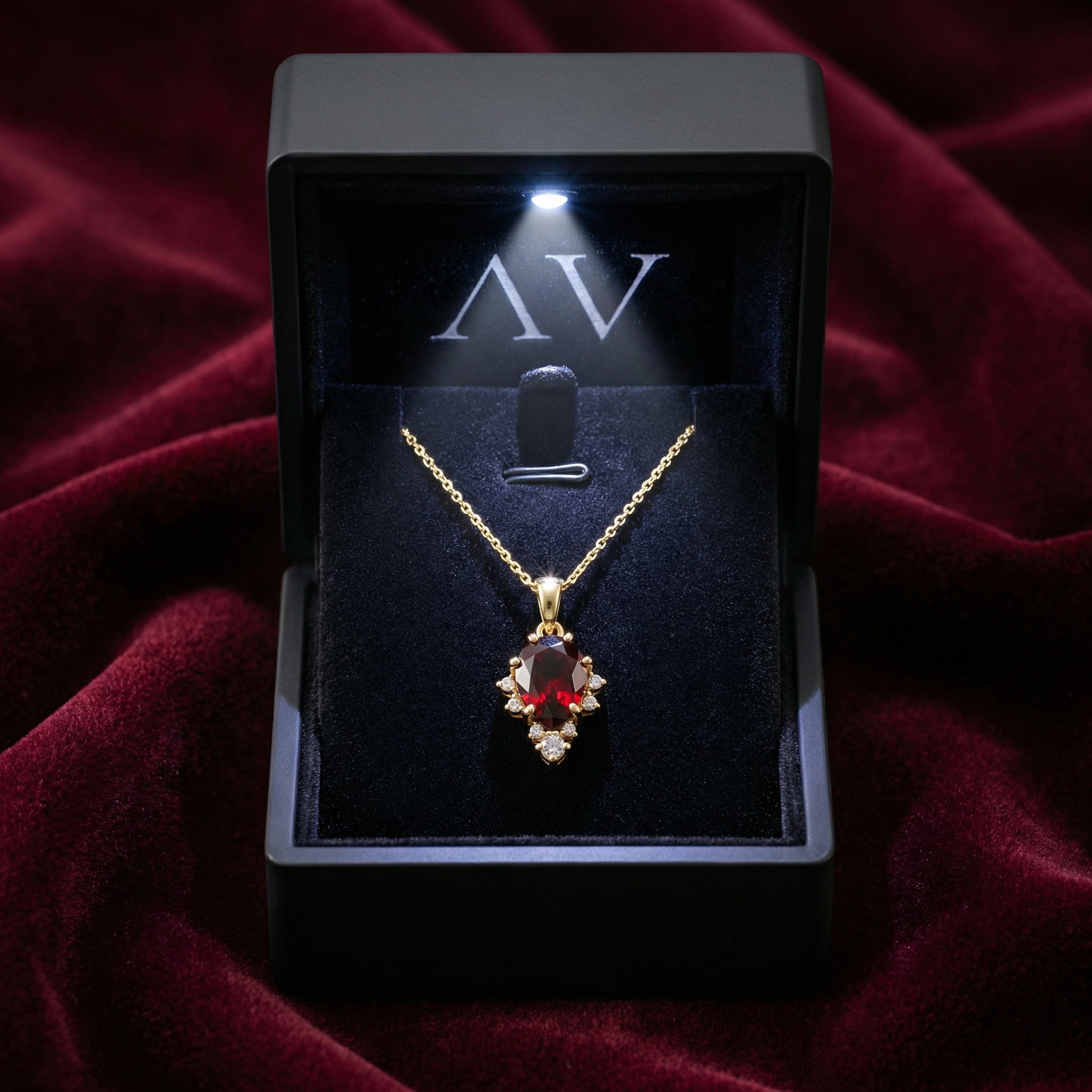 18K gold vermeil teardrop garnet necklace presented in a lighted black jewelry box on red velvet.