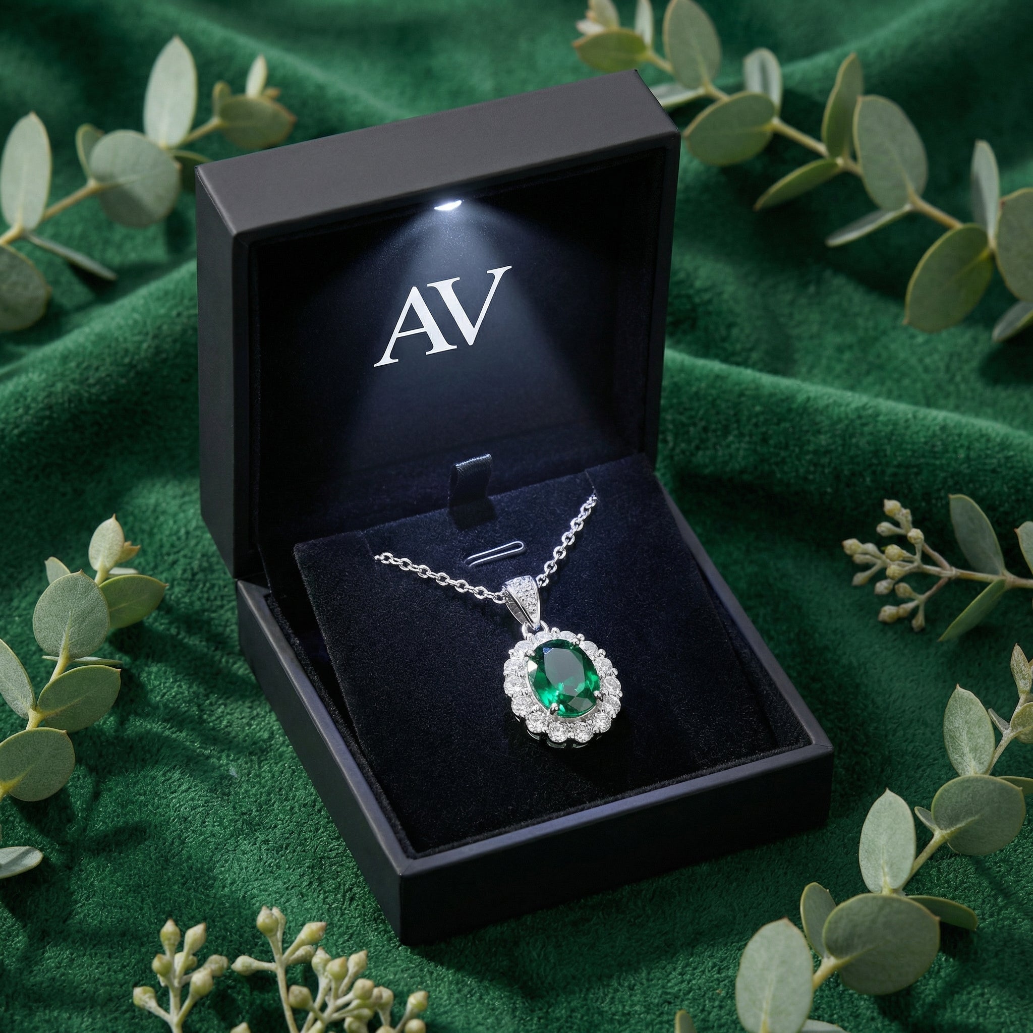 Simulated emerald halo necklace presented in a black LED-lit jewelry gift box on green velvet.
