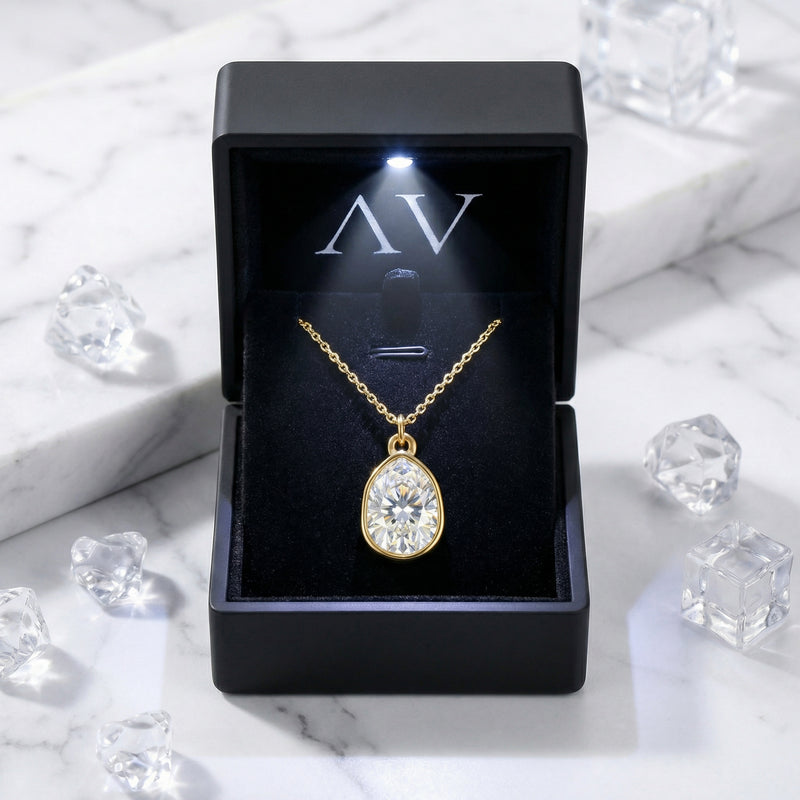 Pear-cut zirconia necklace in a gold-finished stainless steel setting inside a black lighted jewelry gift box.