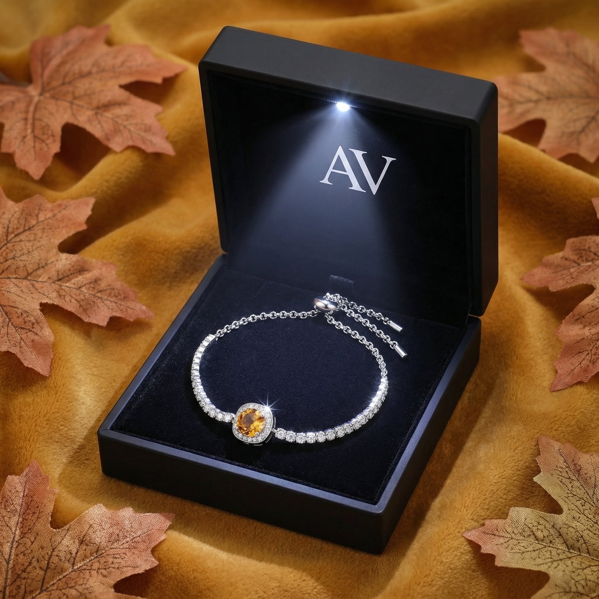 Sterling silver simulated topaz halo bracelet inside a black LED-lit gift box on an autumn-themed background.