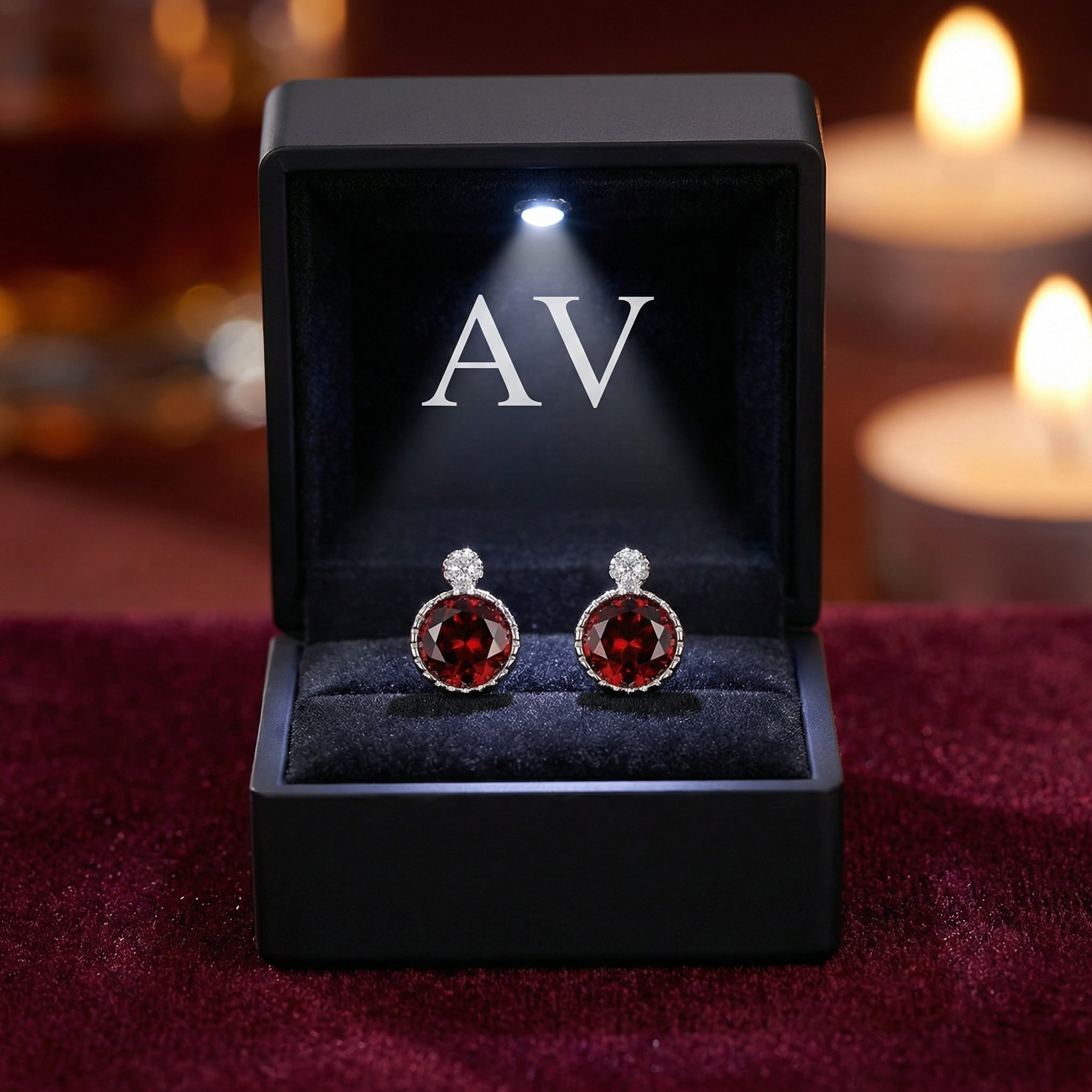 Red garnet halo stud earrings in sterling silver presented in a black gift box with an integrated LED light.