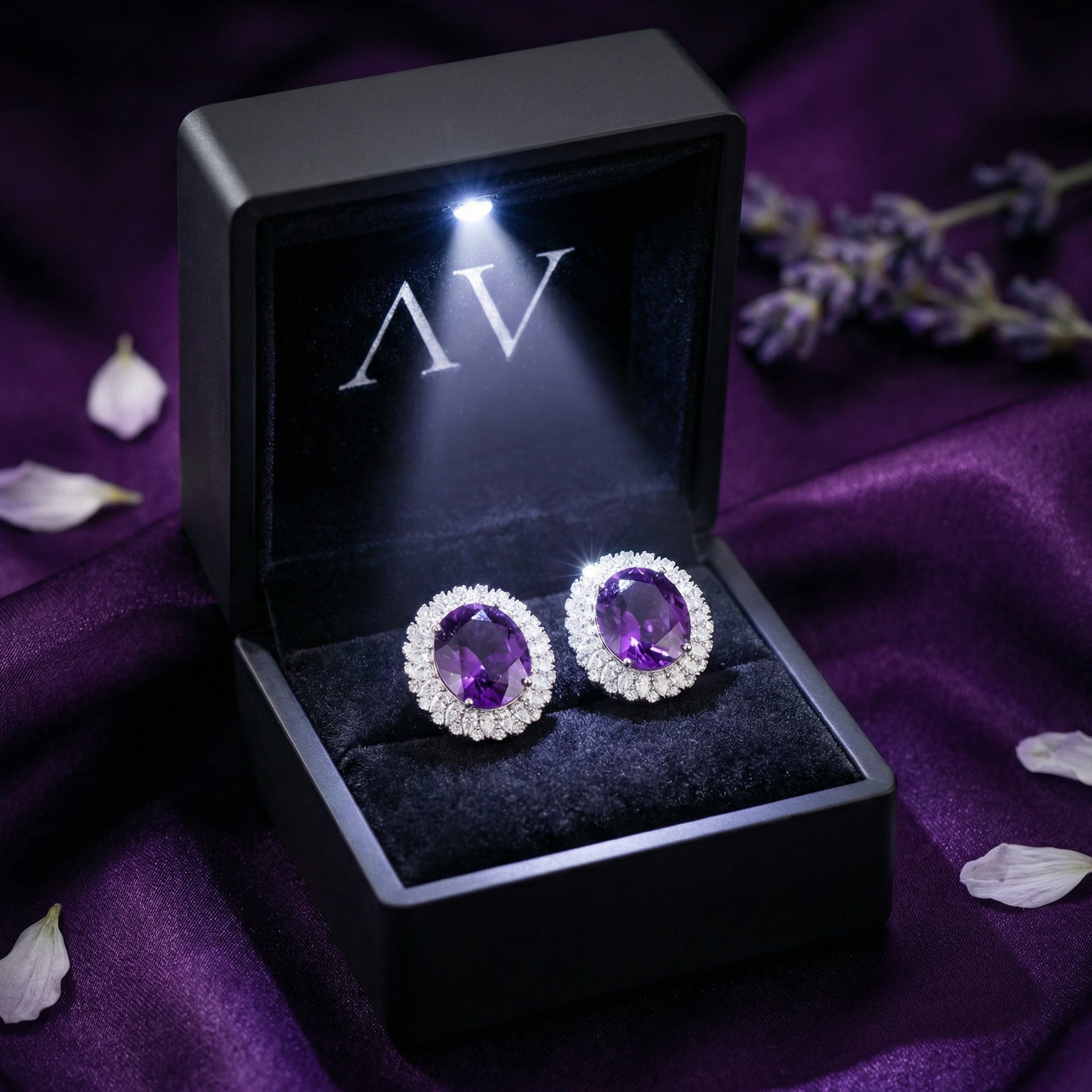 Pair of oval natural amethyst halo earrings inside a black LED-lit gift box on purple silk.
