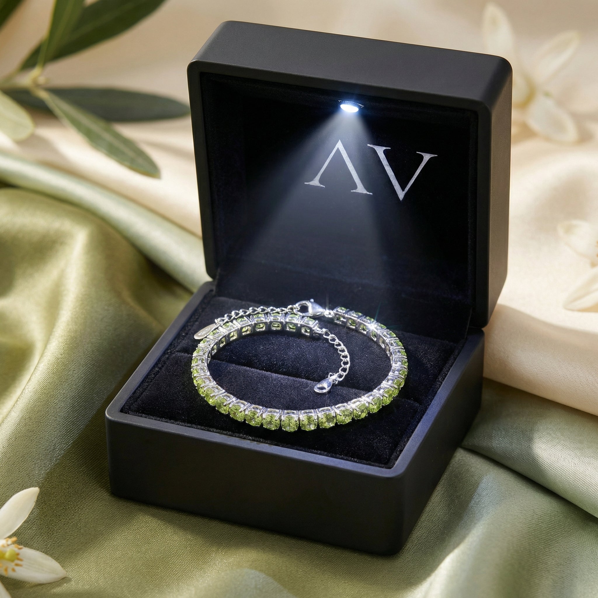 Sterling silver natural peridot tennis bracelet inside a black LED-lit jewelry gift box.