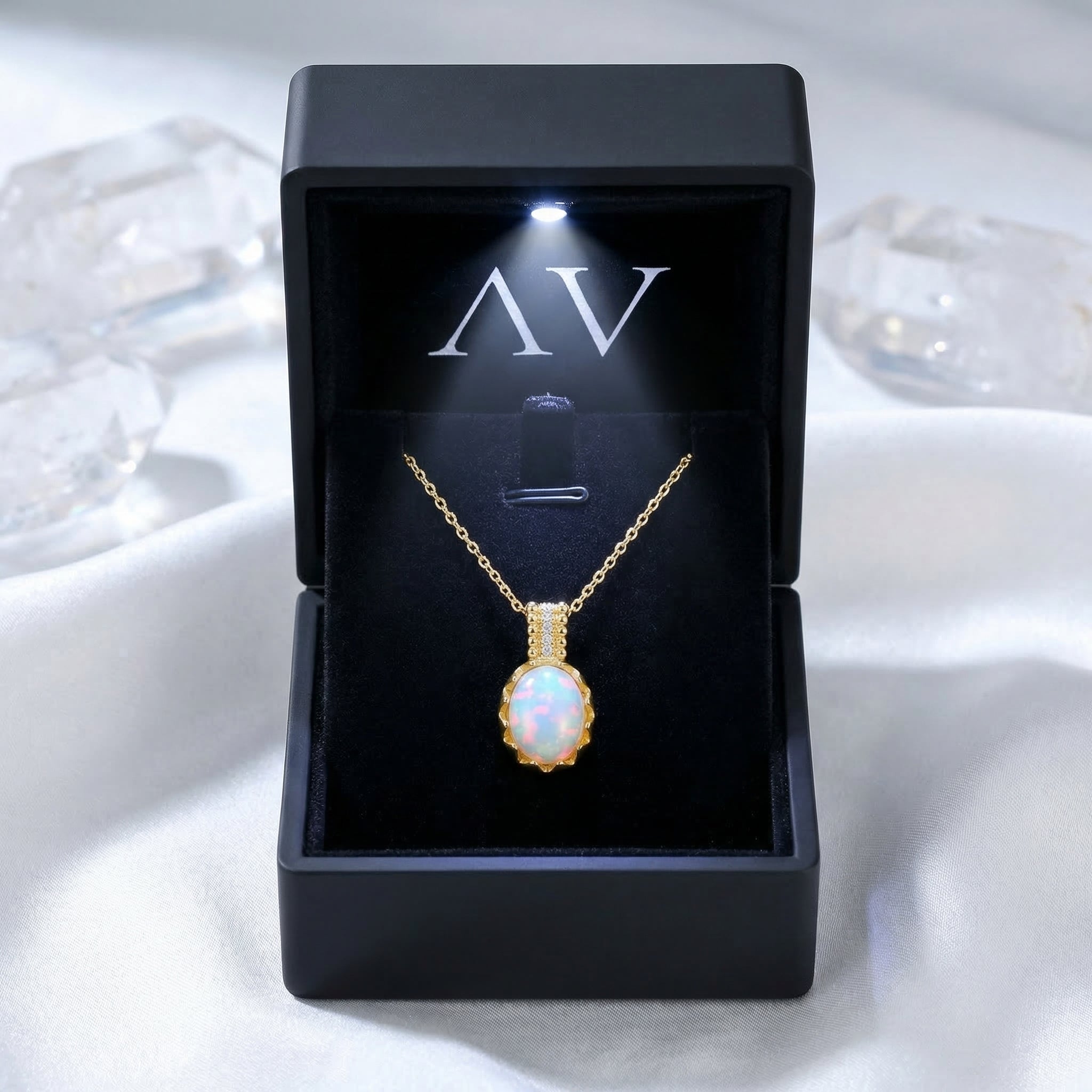 Gold-tone Orianthi opal necklace displayed in a black branded gift box with an integrated LED spotlight.
