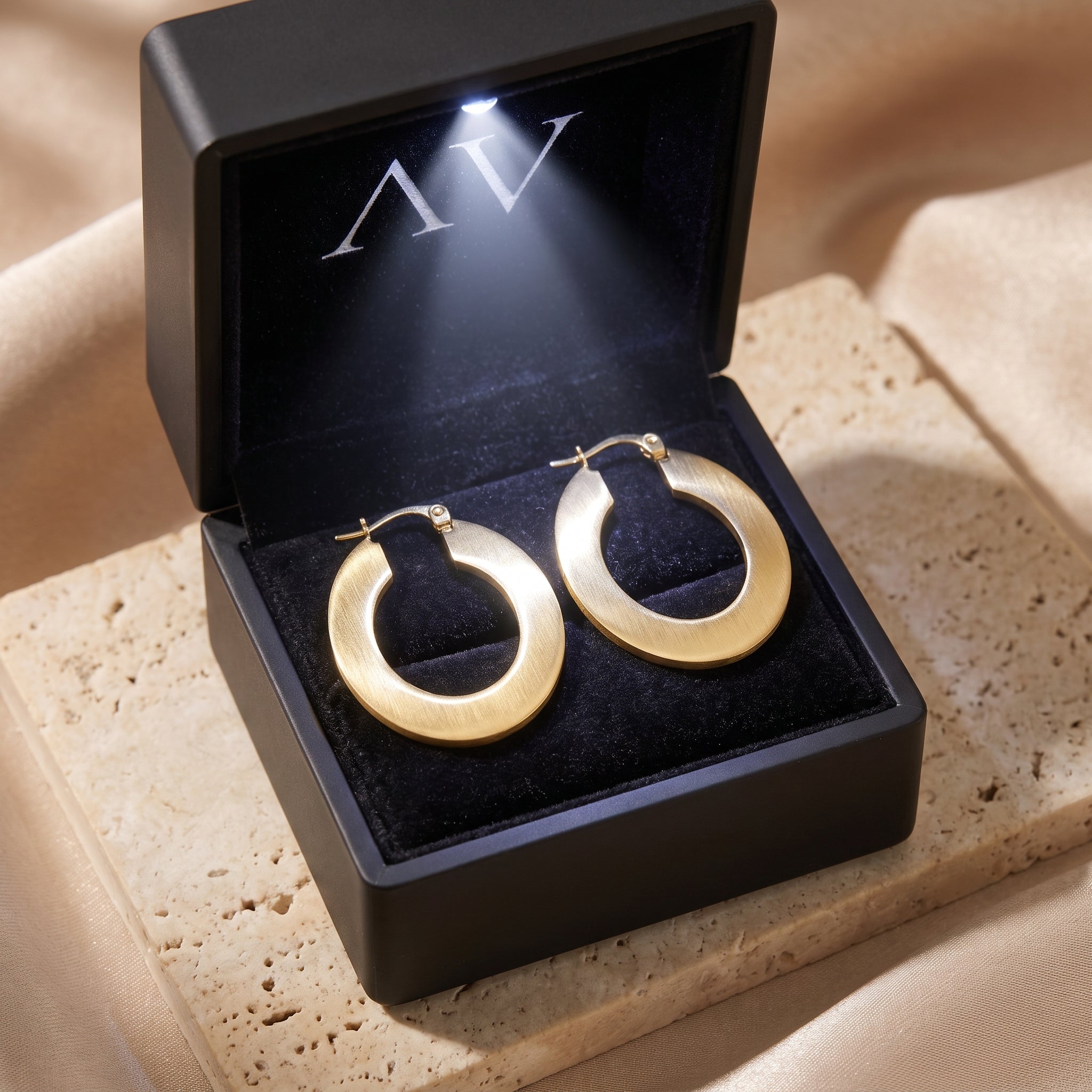 Matte 18K gold PVD hoop earrings presented in a black LED-lit premium jewelry box.