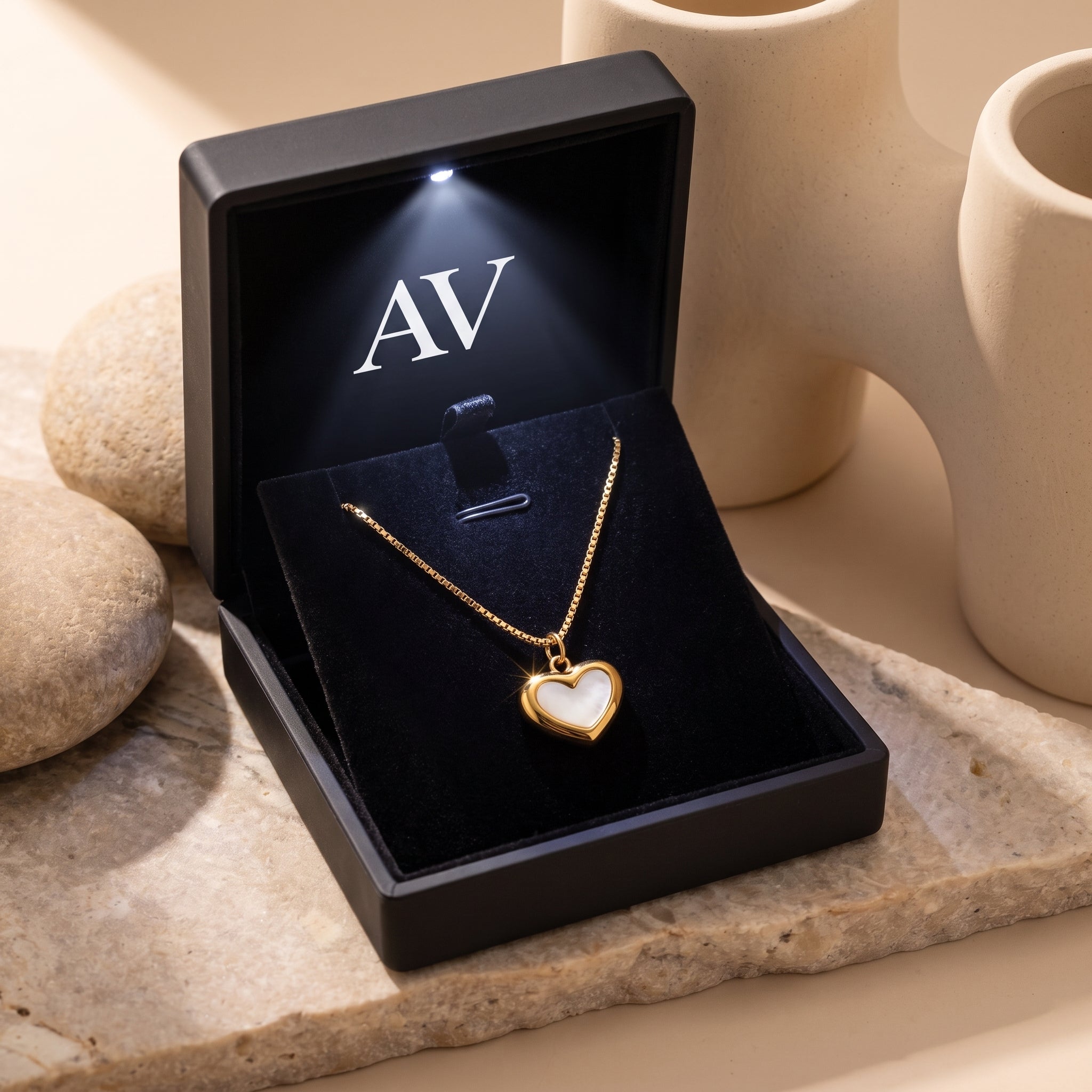 Gold heart necklace with white inlay inside a premium black LED-lit presentation box.
