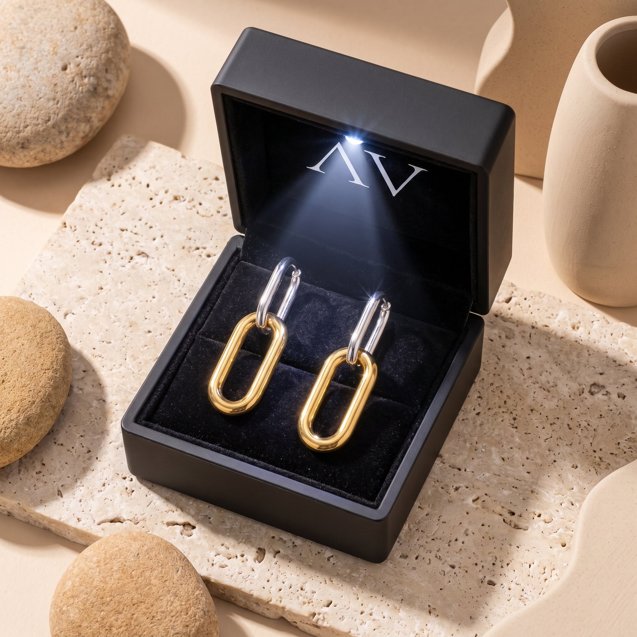 Two-tone stainless steel drop earrings inside a black LED-lit jewelry gift box.