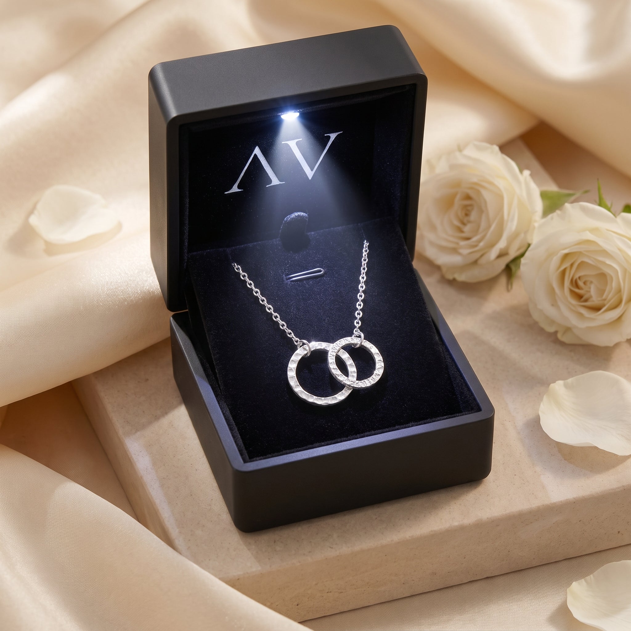 Silver interlocking circle necklace inside a black LED-lit jewelry presentation box.