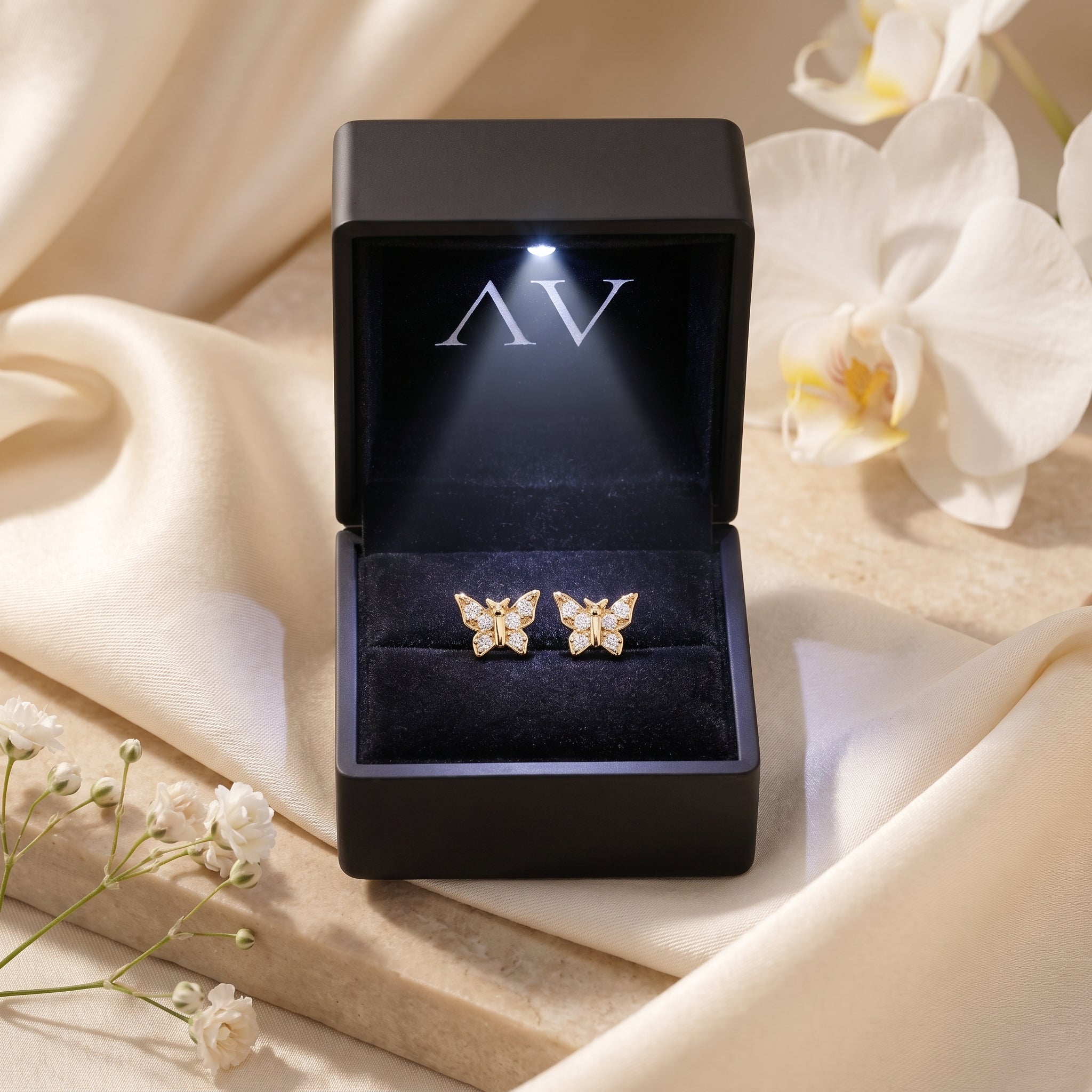 Gold butterfly earrings in lighted black gift box.