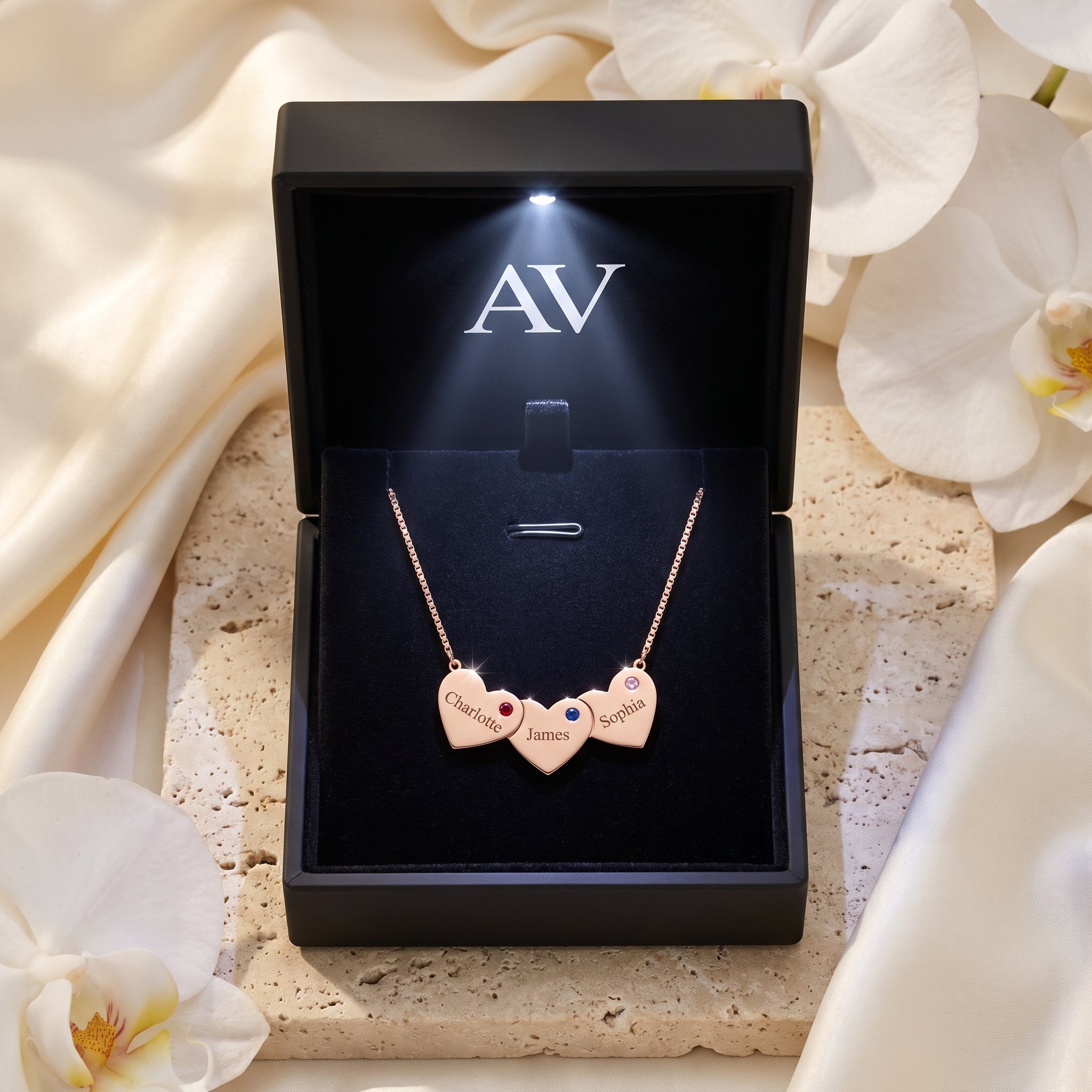 Rose gold Sybilla necklace with three heart pendants in a black LED-lit jewelry gift box with white orchids.