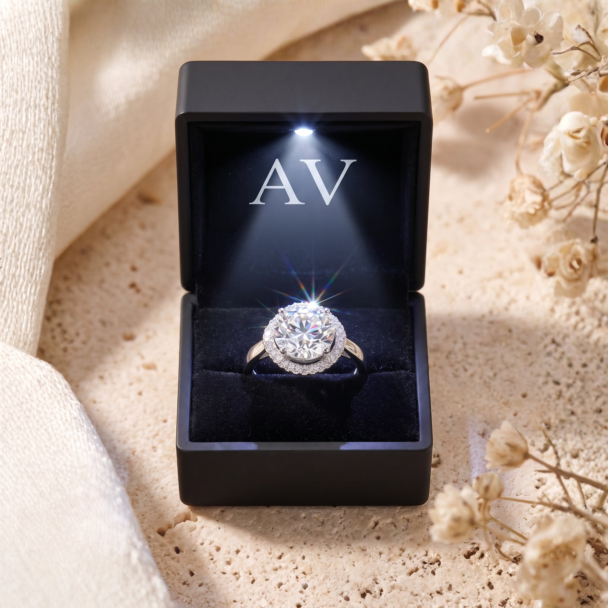 Sterling silver halo ring in a black LED-lit gift box on a stone surface.