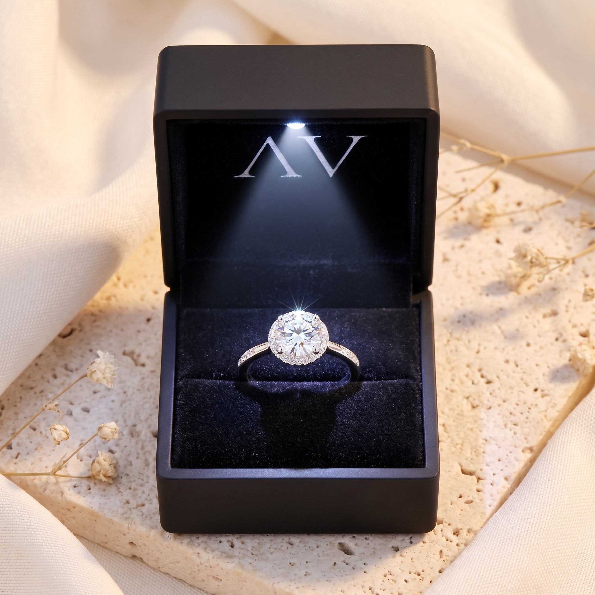 Silver round halo ring inside a black LED-lit jewelry presentation box.