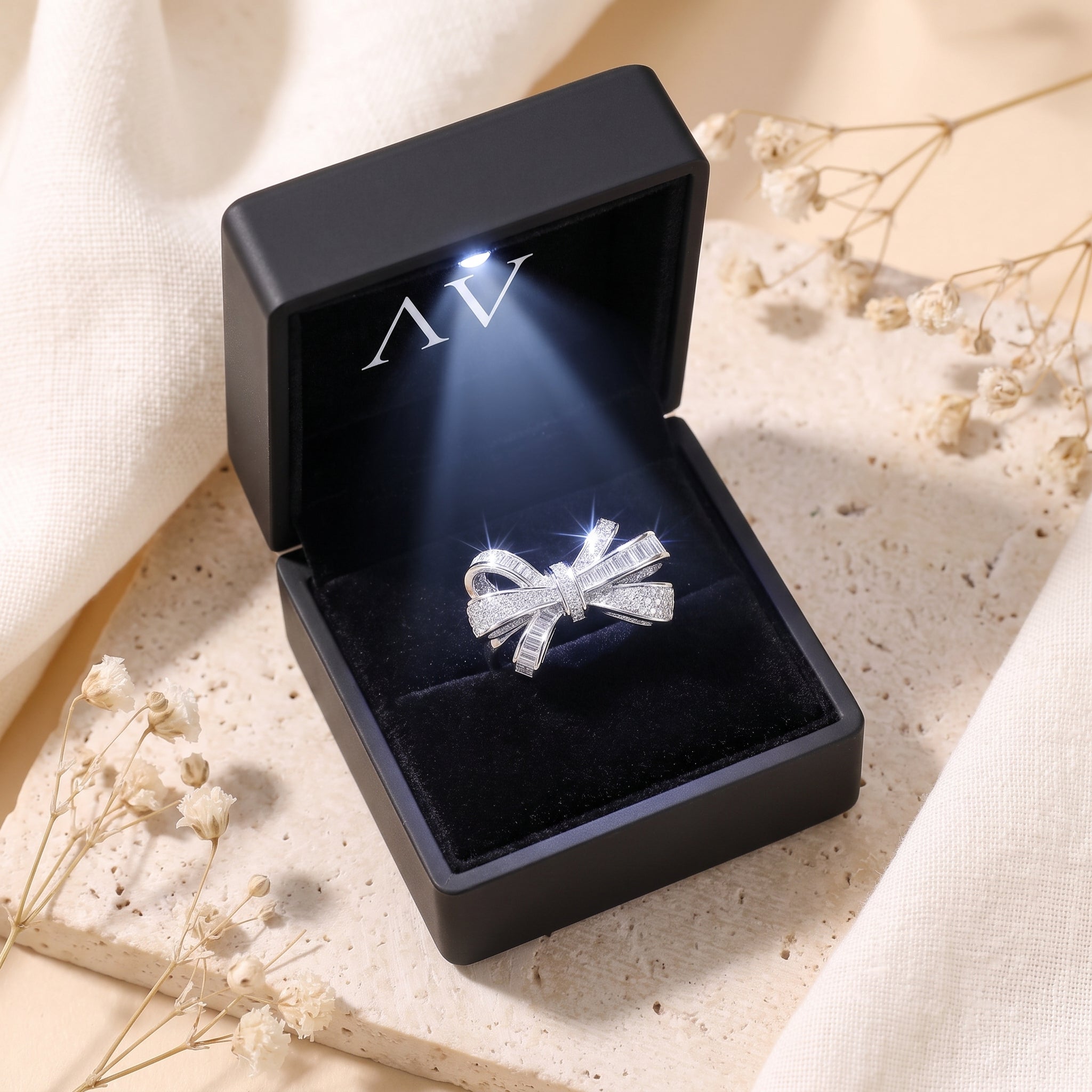 Sterling silver bow ring presented in a black LED-lit jewelry gift box.