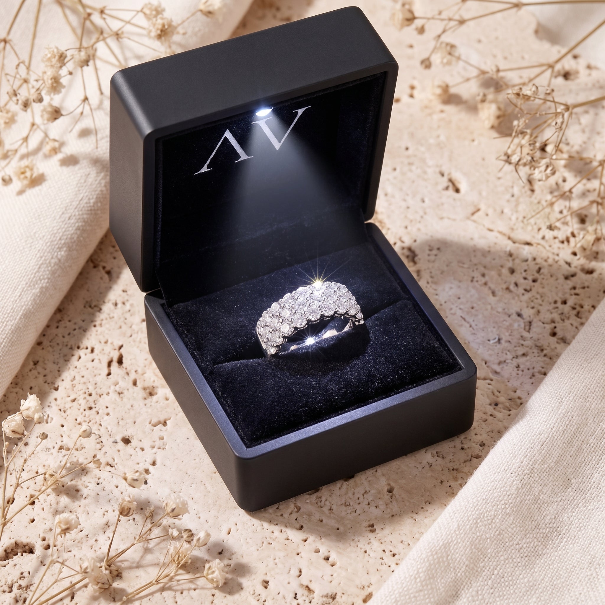 Multi-row cubic zirconia pavé ring in a lighted black jewelry presentation box.