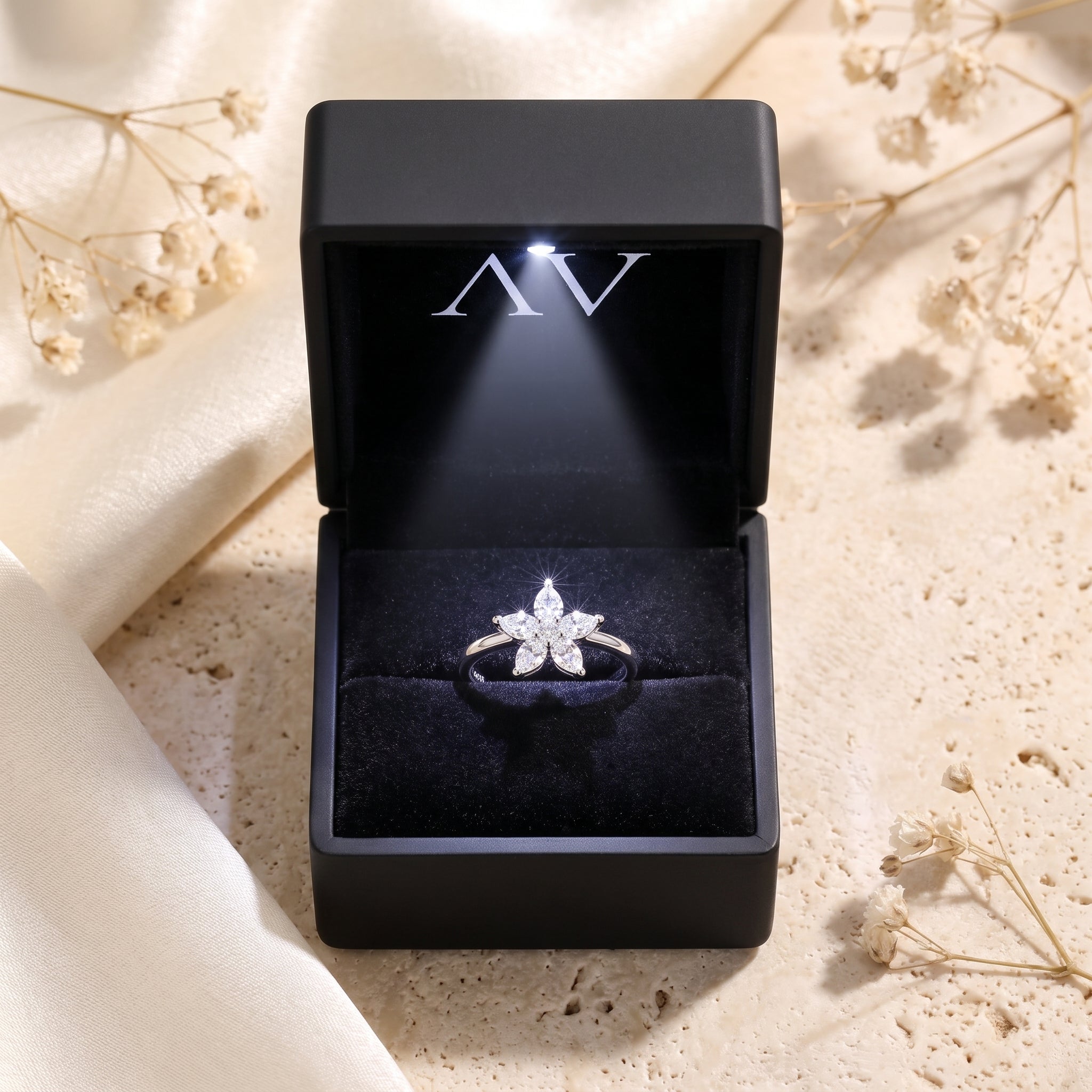 Silver flower cluster ring inside a black LED-lit presentation box.