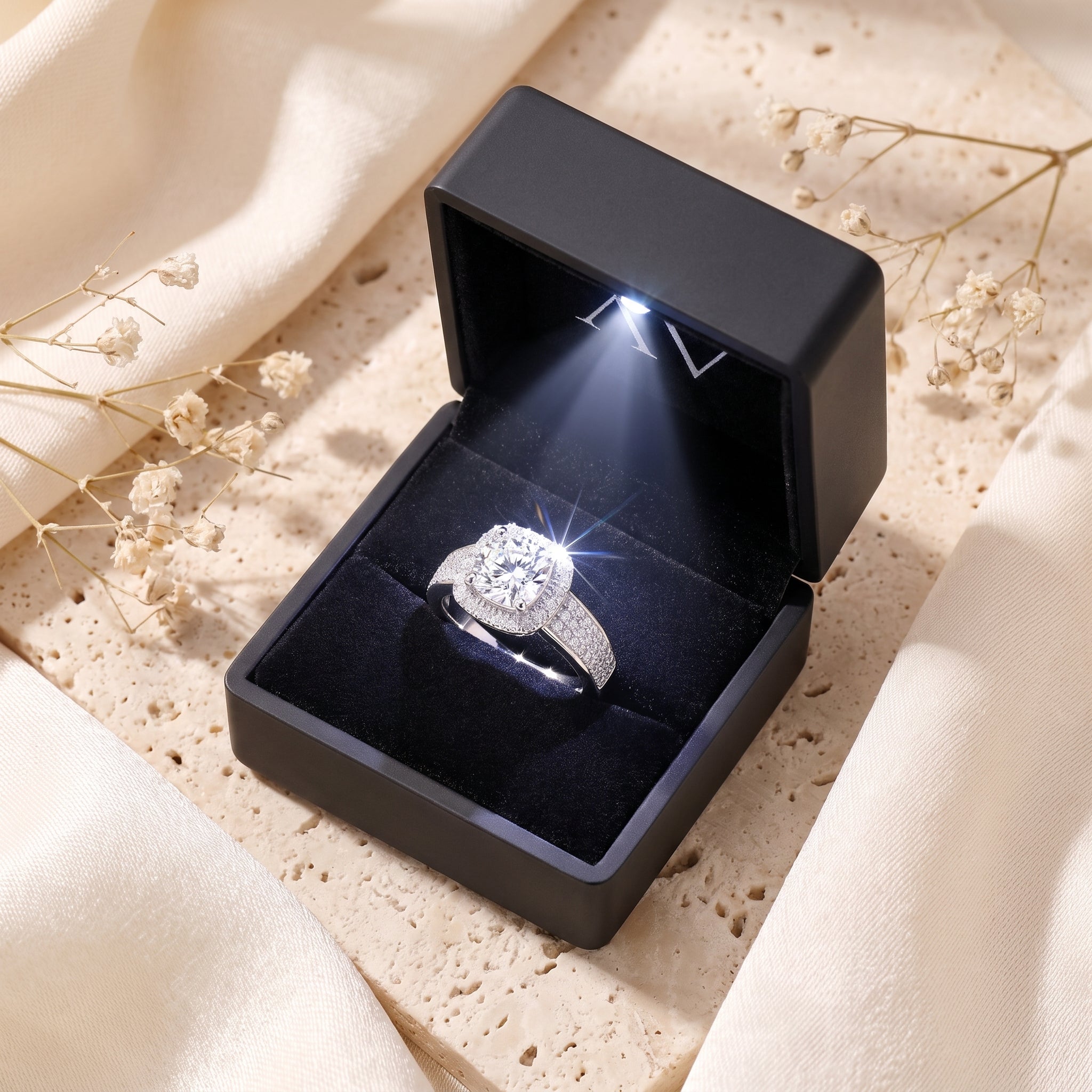 Silver cushion halo ring in a black lighted gift box.