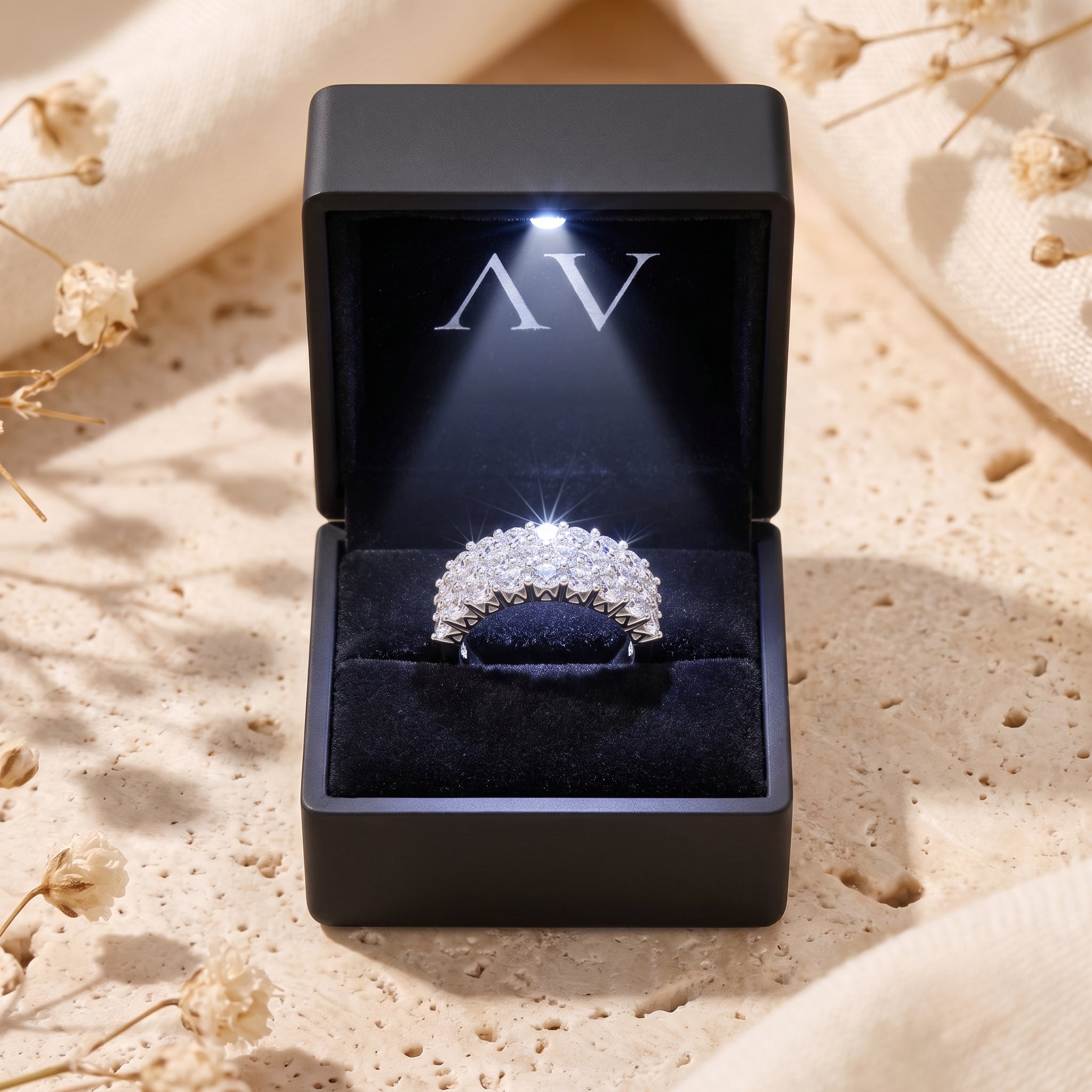 Triple row sterling silver ring with round cubic zirconia inside a lighted black gift box.