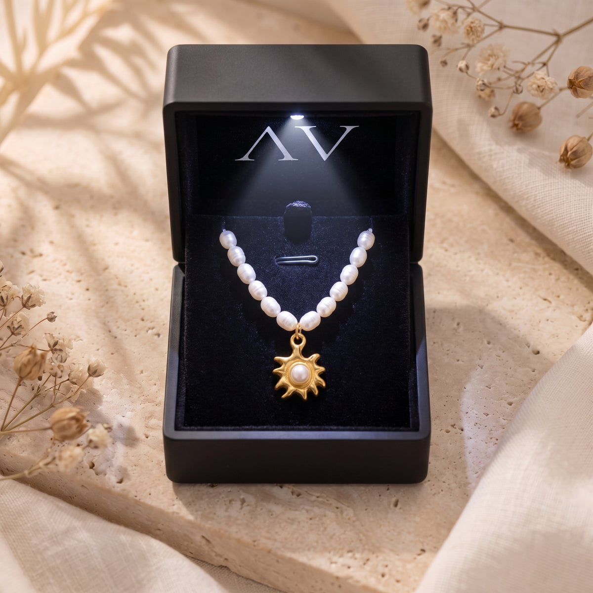 Gold sunburst pearl necklace presented in a premium black LED-lit jewelry gift box.