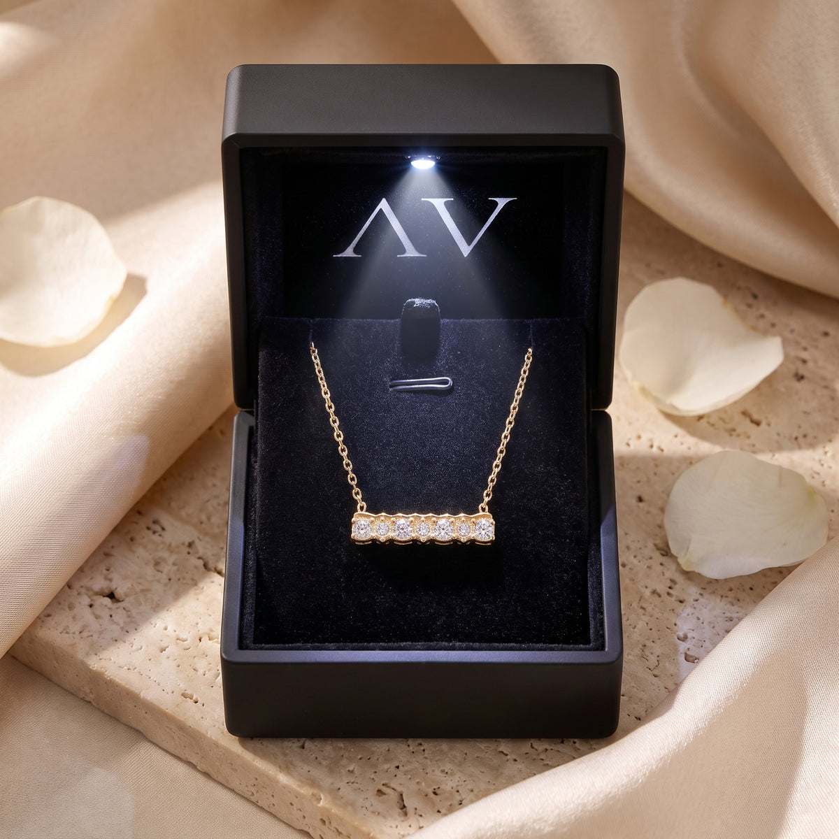 Gold bar pendant necklace with seven stones displayed in a black LED-lit jewelry gift box.