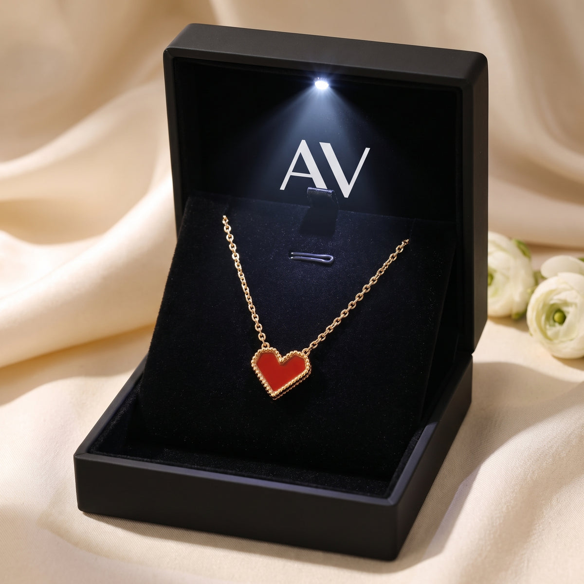 Gold heart necklace with scarlet inlay inside a black LED-lit presentation box.