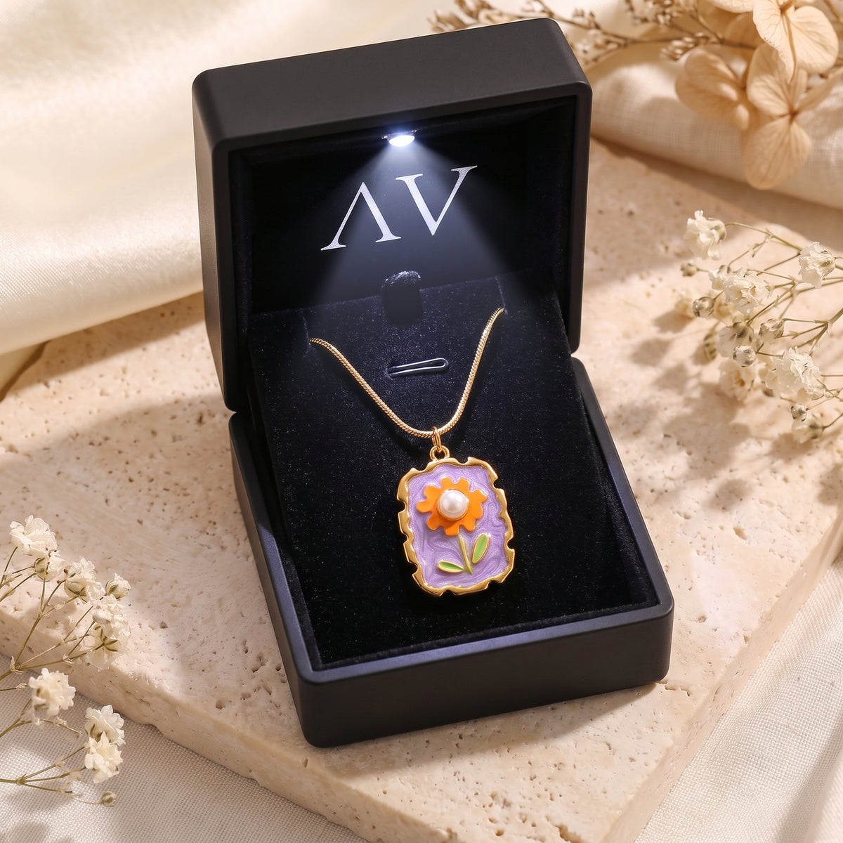 Gold Amorina pearl necklace presented in a premium black LED-lighted gift box on a stone surface.