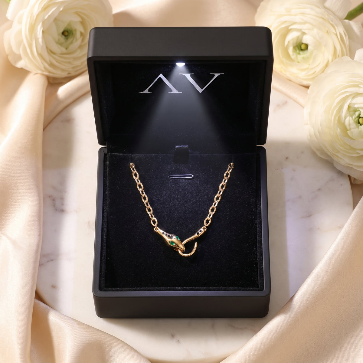 Gold Serpentine Necklace displayed in a premium black LED-lit jewelry gift box with white floral accents.