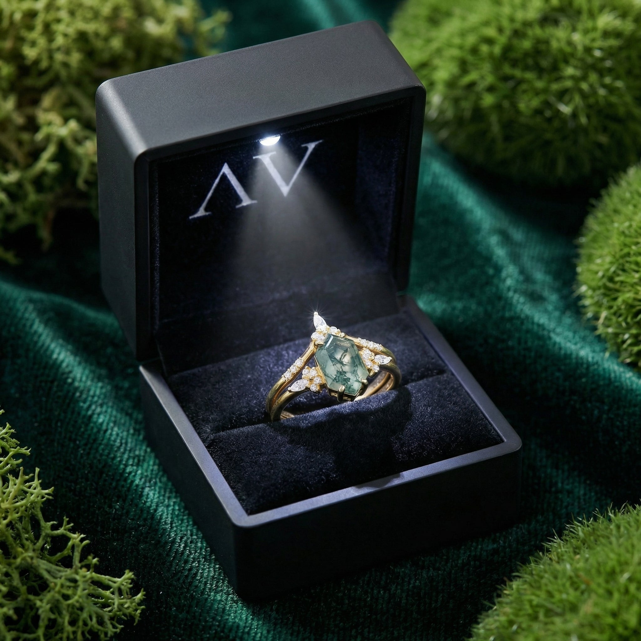 Hexagonal moss agate gold ring set presented in a black LED lighted gift box on green velvet.