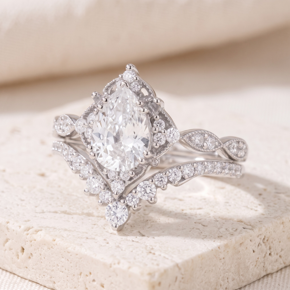 Vintage pear-cut ring and matching curved band in silver, three-quarter closeup.