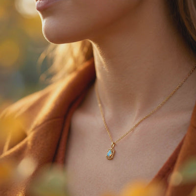 Woman wearing a solid gold necklace with a pear-shaped opal pendant.