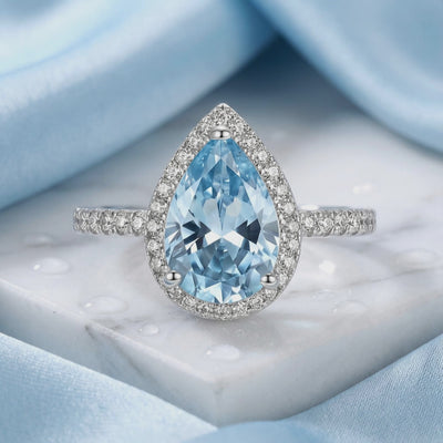 Pear halo simulated aquamarine ring in solid gold.