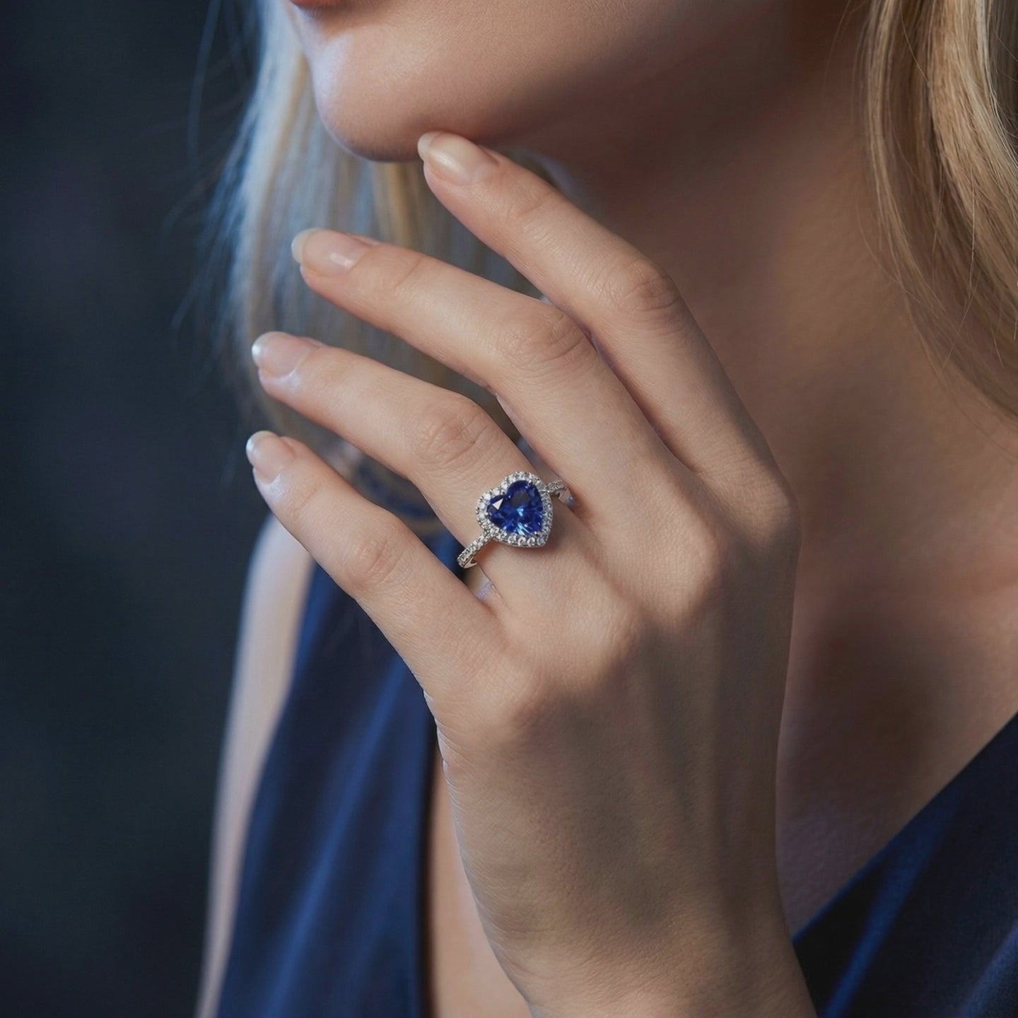 Heart-shaped tanzanite halo ring in solid white gold, worn on a hand.