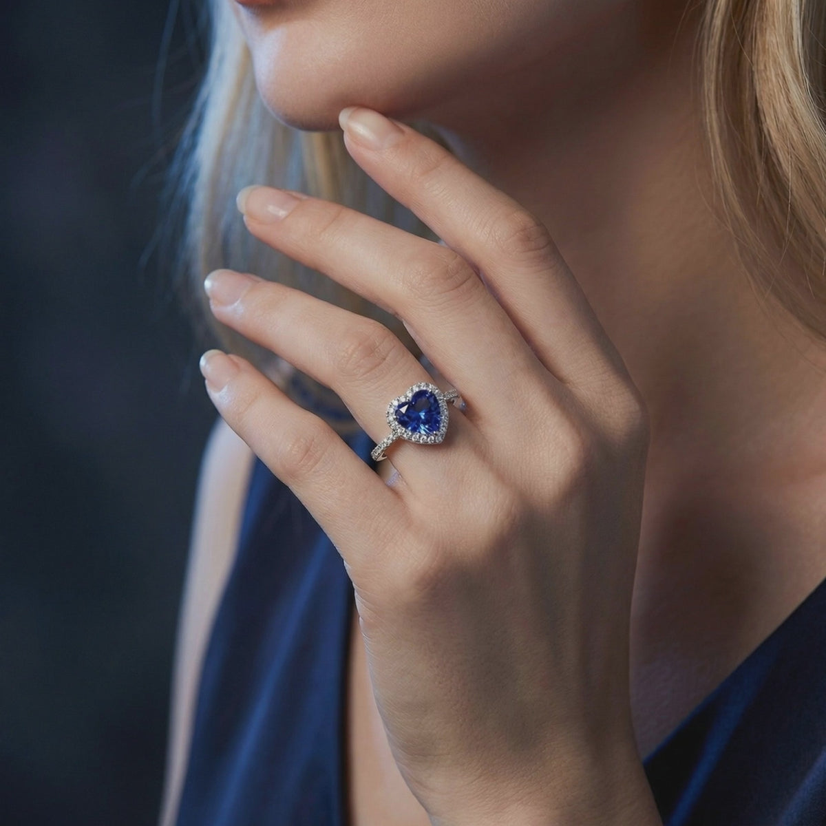 Heart-shaped tanzanite halo ring in solid white gold, worn on a hand.