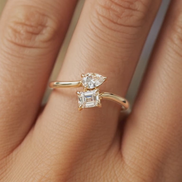 The Melora Muse solid gold ring featuring a Toi et Moi design with emerald and pear cut moissanite stones.