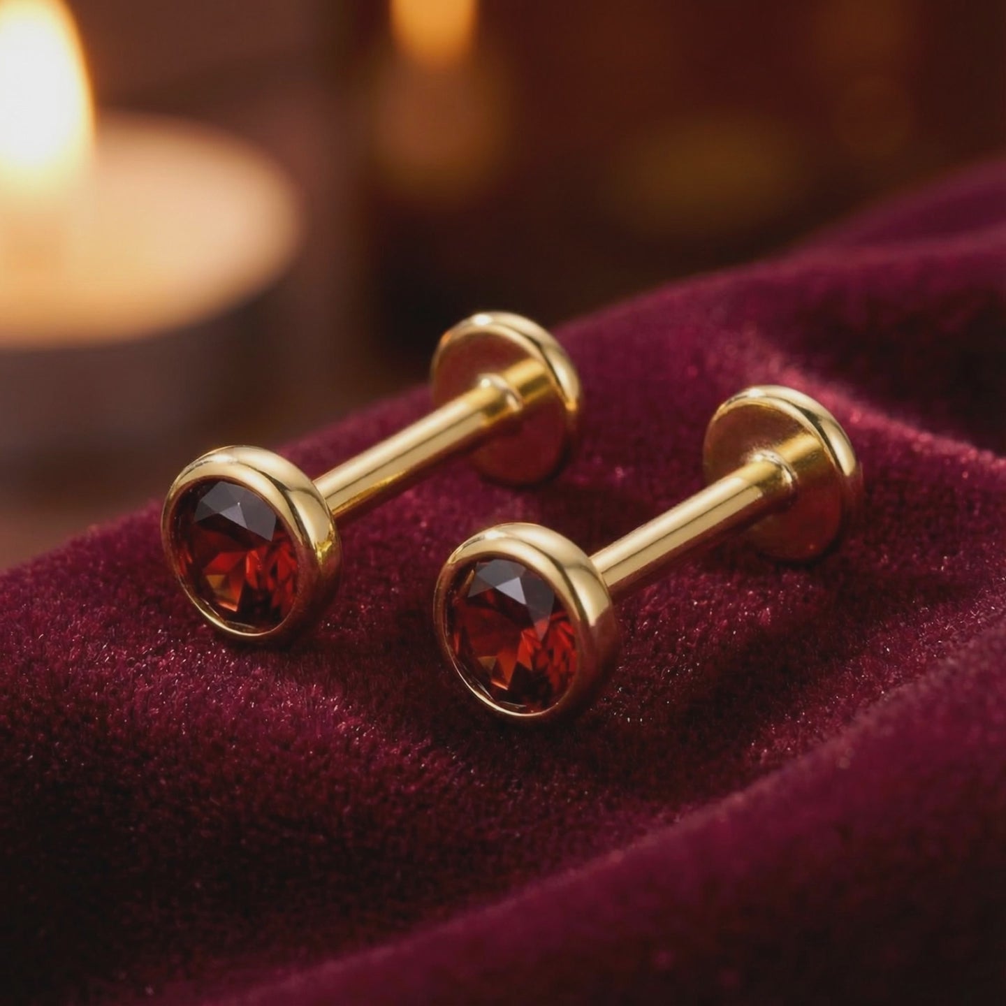 Close-up showcase of precision-cut simulated garnet stud earrings in solid gold.