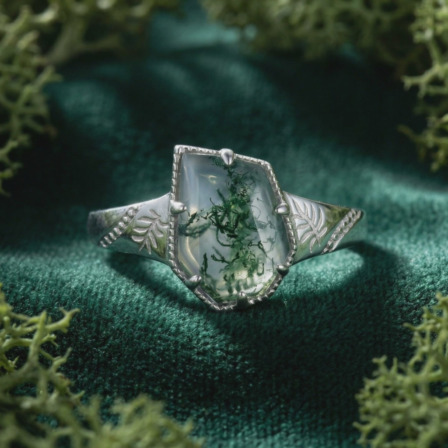 A solid white gold moss agate ring with a leaf design.