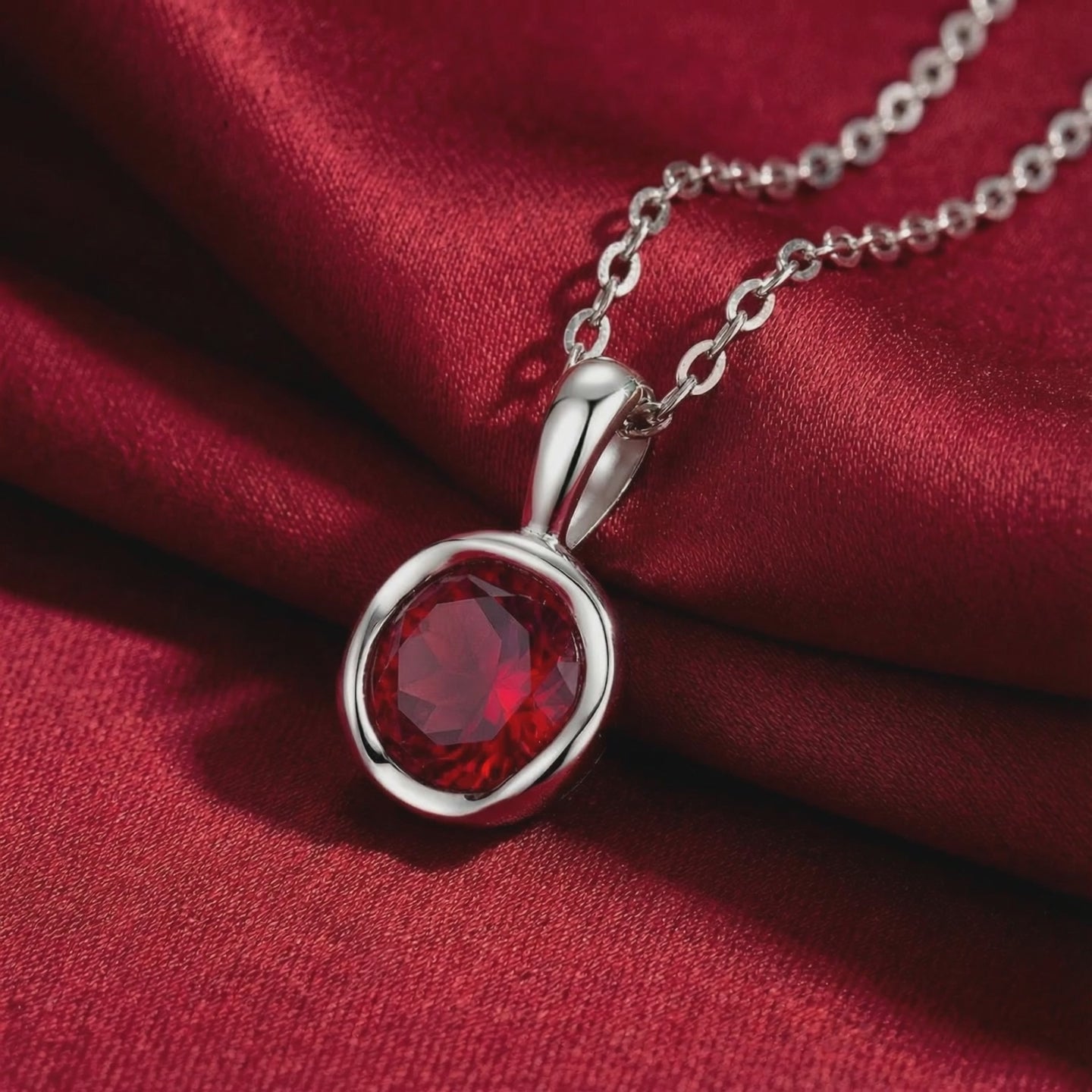 Close-up of a solid gold necklace featuring a round bezel-set simulated ruby pendant.