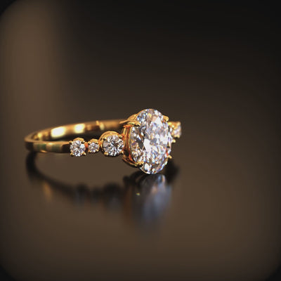 A solid gold ring with an oval moissanite center stone and round side stones.