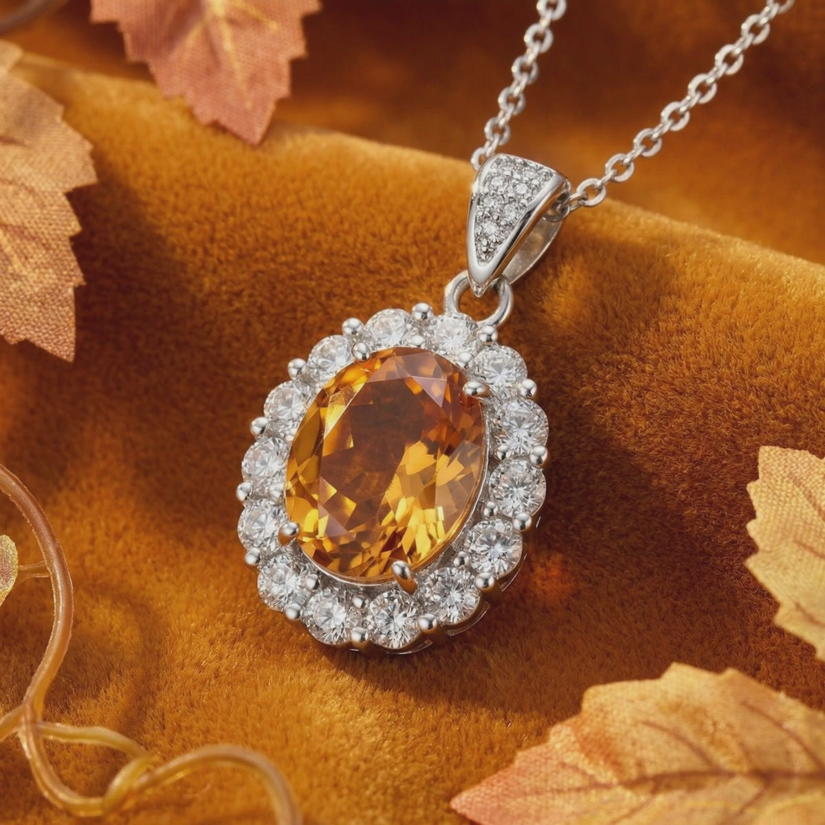 Close-up of an oval golden-orange simulated topaz pendant with a clear-stone halo in solid white gold.