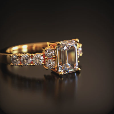 A solid gold ring with an emerald cut moissanite