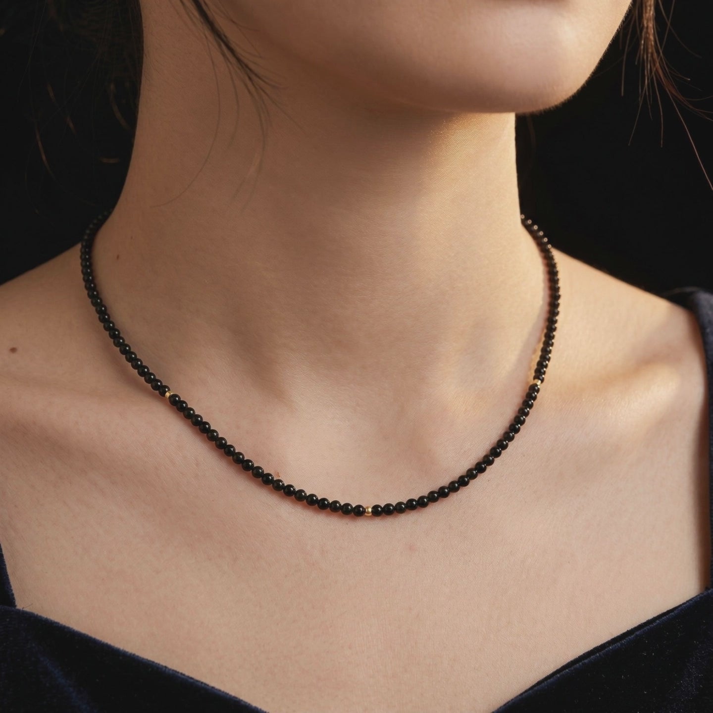 A solid gold necklace with natural black onyx beads.