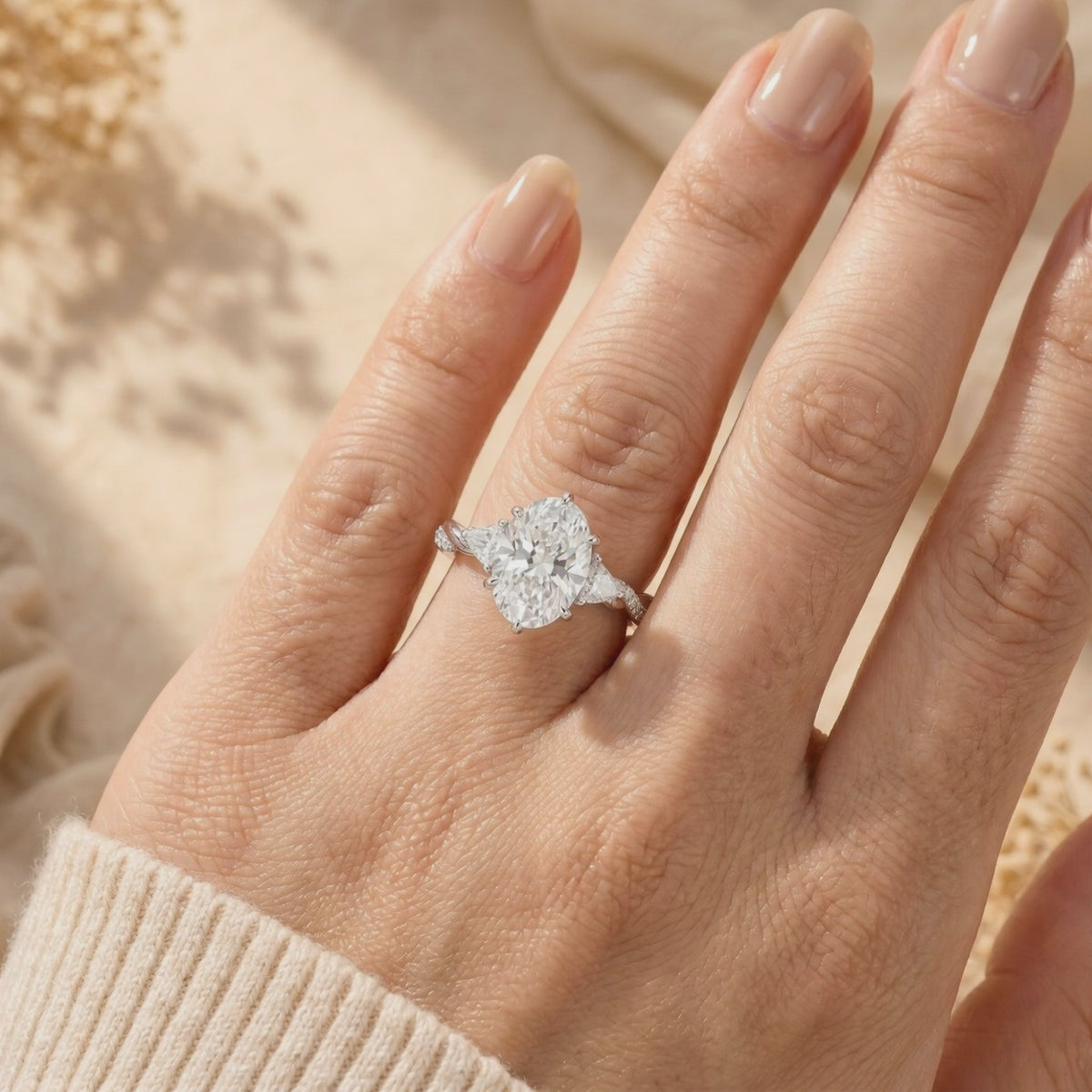 Oval moissanite ring with a twisted solid gold band worn on a finger.