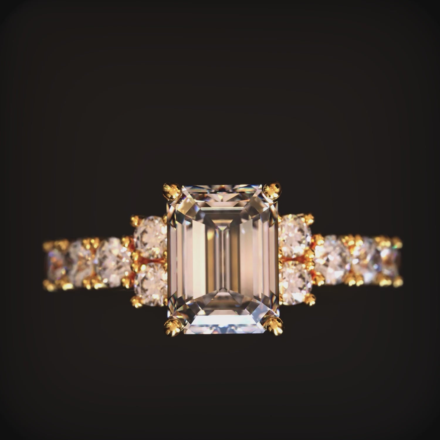 A solid gold ring with an emerald cut moissanite