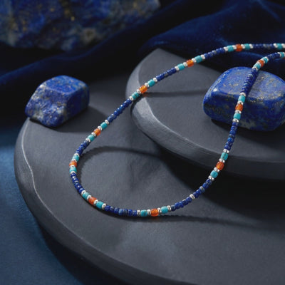 Solid gold lapis lazuli bead necklace arranged on dark display trays.